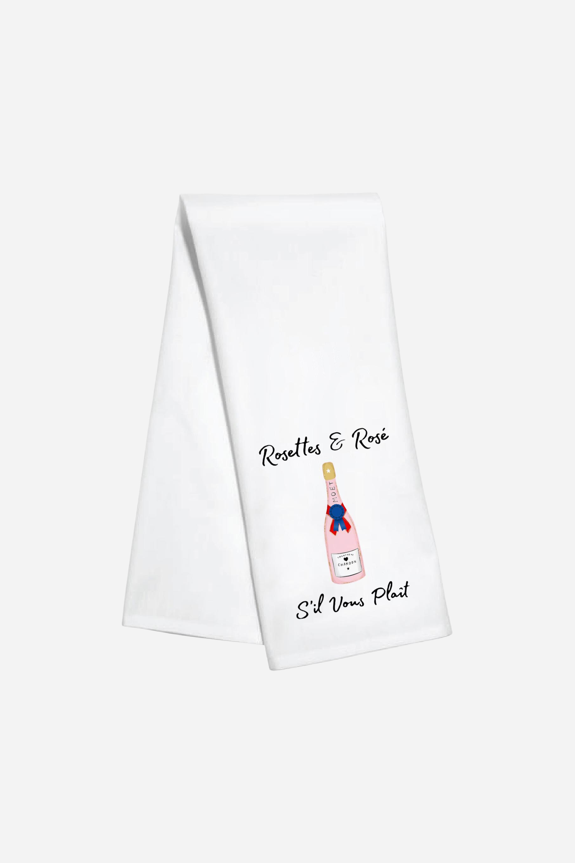 Toss Designs Rosettes & Rosé Hand Towel
| White kitchen towel with a playful illustration of a pink bottle of rosé wine, adorned with a blue and red ribbon. Text reads "Rosettes & Rosé S'il Vous Plaît." | Rosettes and Rosé hand towel, equestrian kitchen towel, horse show ribbon tea towel, rosé wine bar towel, horse girl gift, French-inspired tea towel, polyduck hand towel, stylish equestrian home decor, funny horse show towel, made in USA kitchen towel