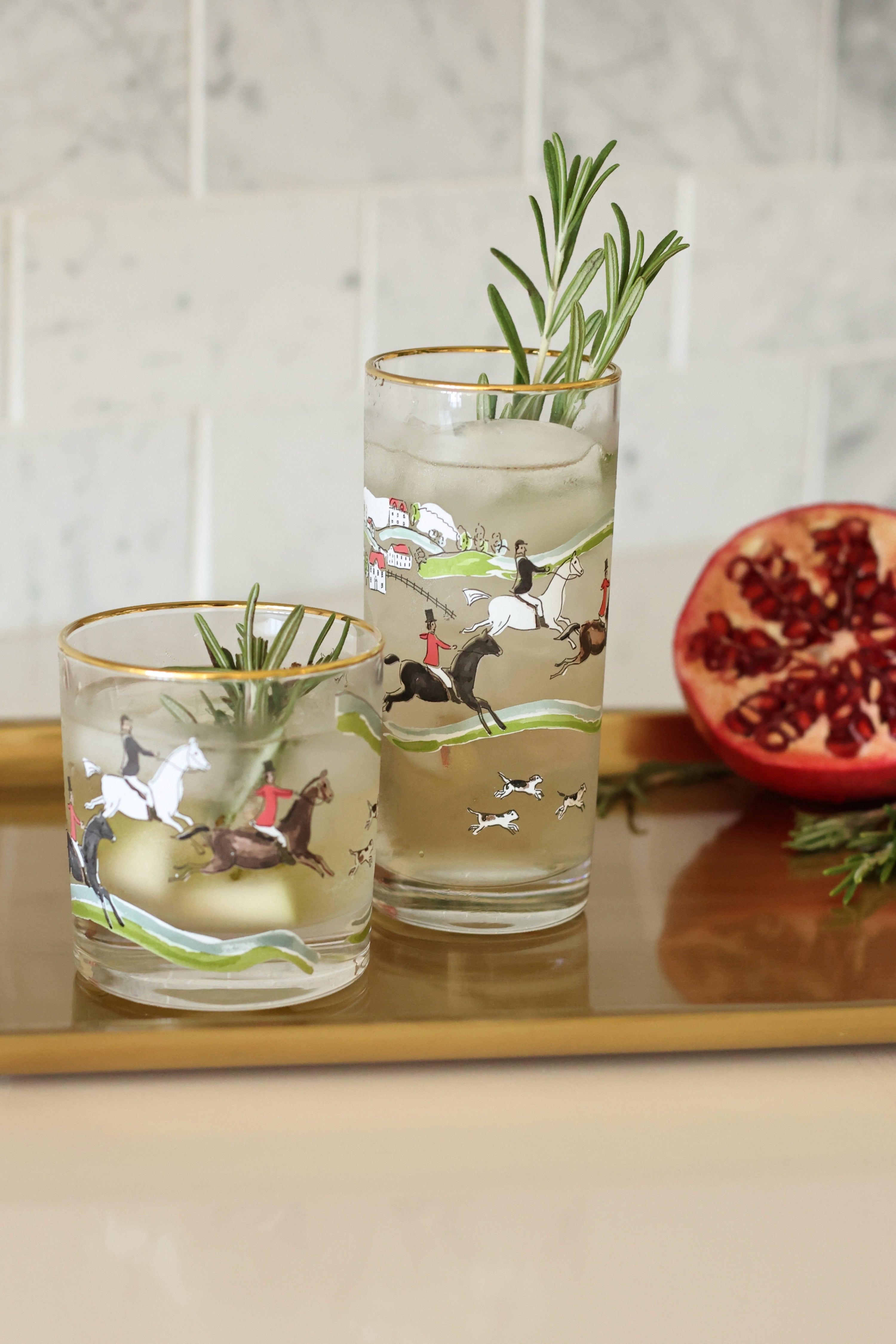 pomegranate inc stylish equestrian hunter drinking glass set The Hunt Scene Drinking Glass Set featuring four tall glasses adorned with a detailed equestrian hunt scene and finished with elegant gold rims. A sophisticated horse-themed glassware set perfect for entertaining or gifting.