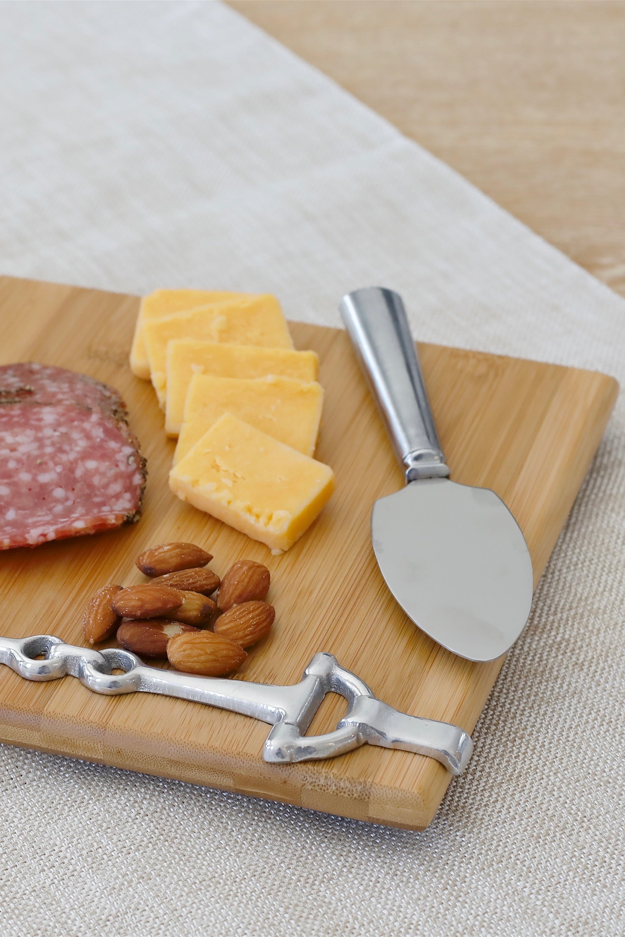 arthur court stylish equestrian well served cheese board snaffle set Well Served Set by Arthur Court featuring a bamboo serving board with a silver alloy horse bit accent, paired with a matching aluminum cheese knife and cracker tray. Elegant equestrian-themed serveware perfect for entertaining or gifting.