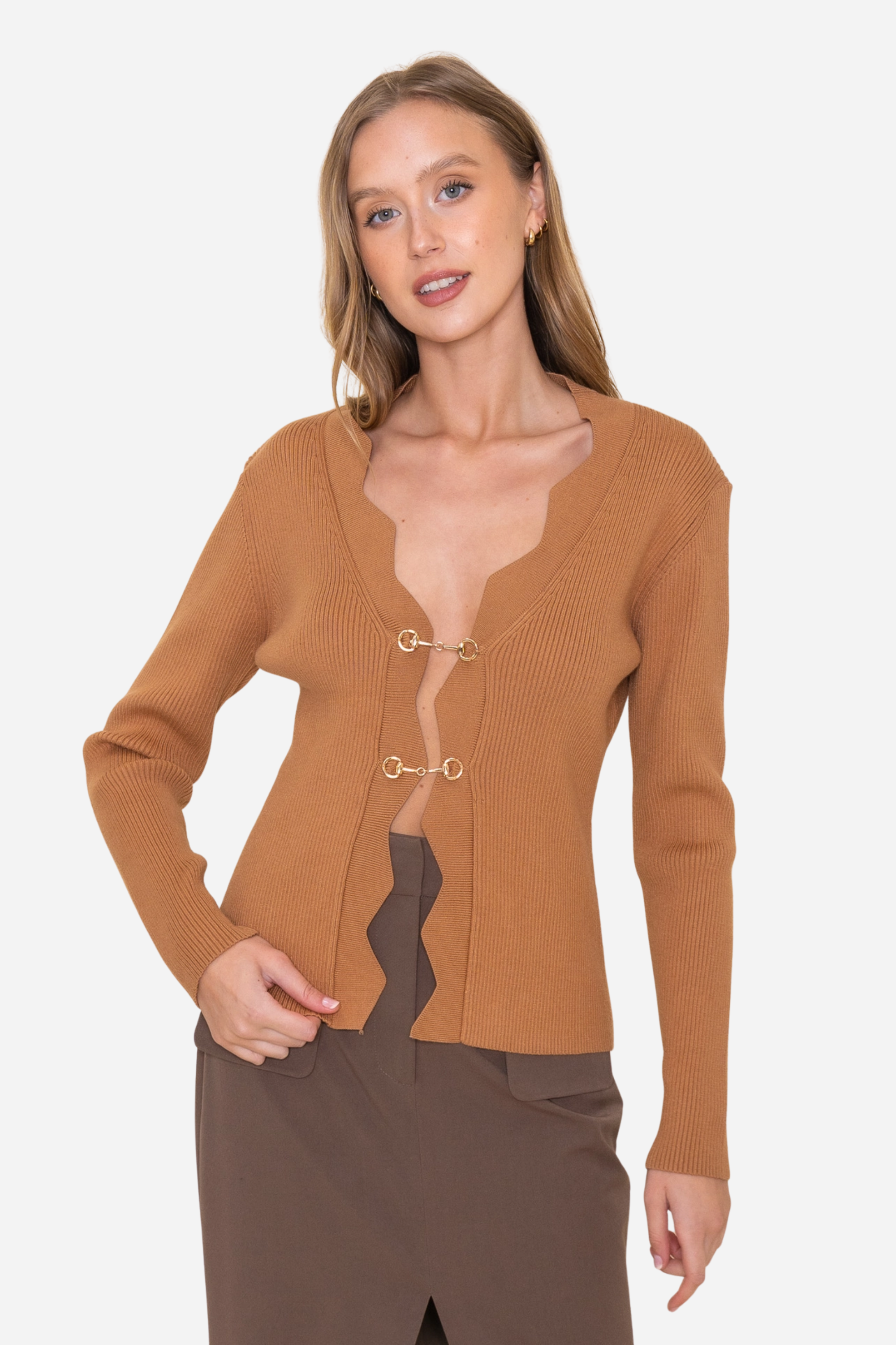 Camel-toned ribbed knit equestrian top featuring a deep scalloped neckline and two gold horsebit closures. Fitted long-sleeve cardigan-style top crafted from a poly/nylon blend, combining timeless elegance with refined equestrian detailing—perfect for fall and winter equestrian fashion.
