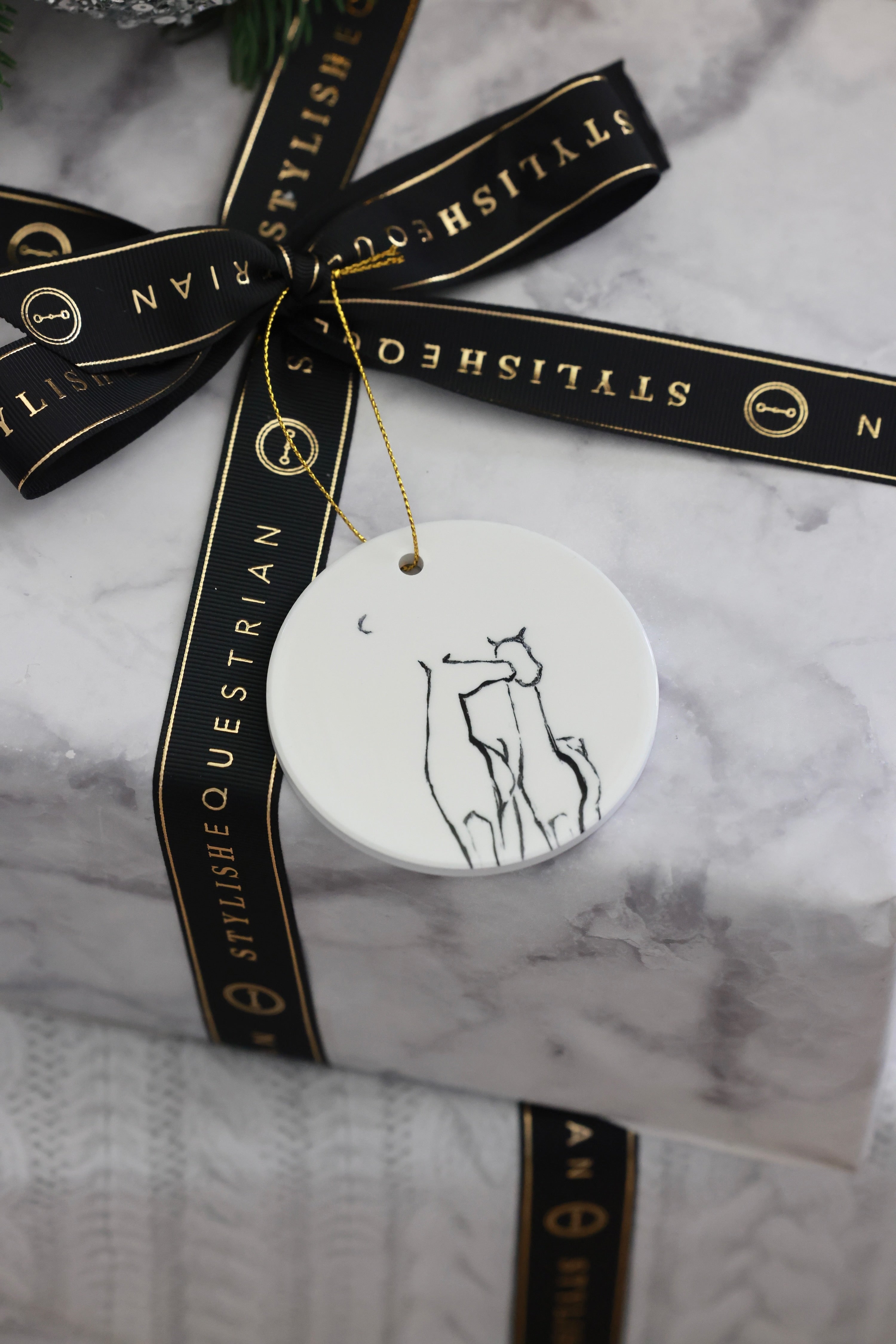 Besos Ornament — ceramic equestrian-inspired Christmas ornament featuring original horse artwork by Bettina, accented with gold tinsel. A charming horse-themed holiday decoration and thoughtful Christmas gift for equestrians and horse lovers. Made in the USA.