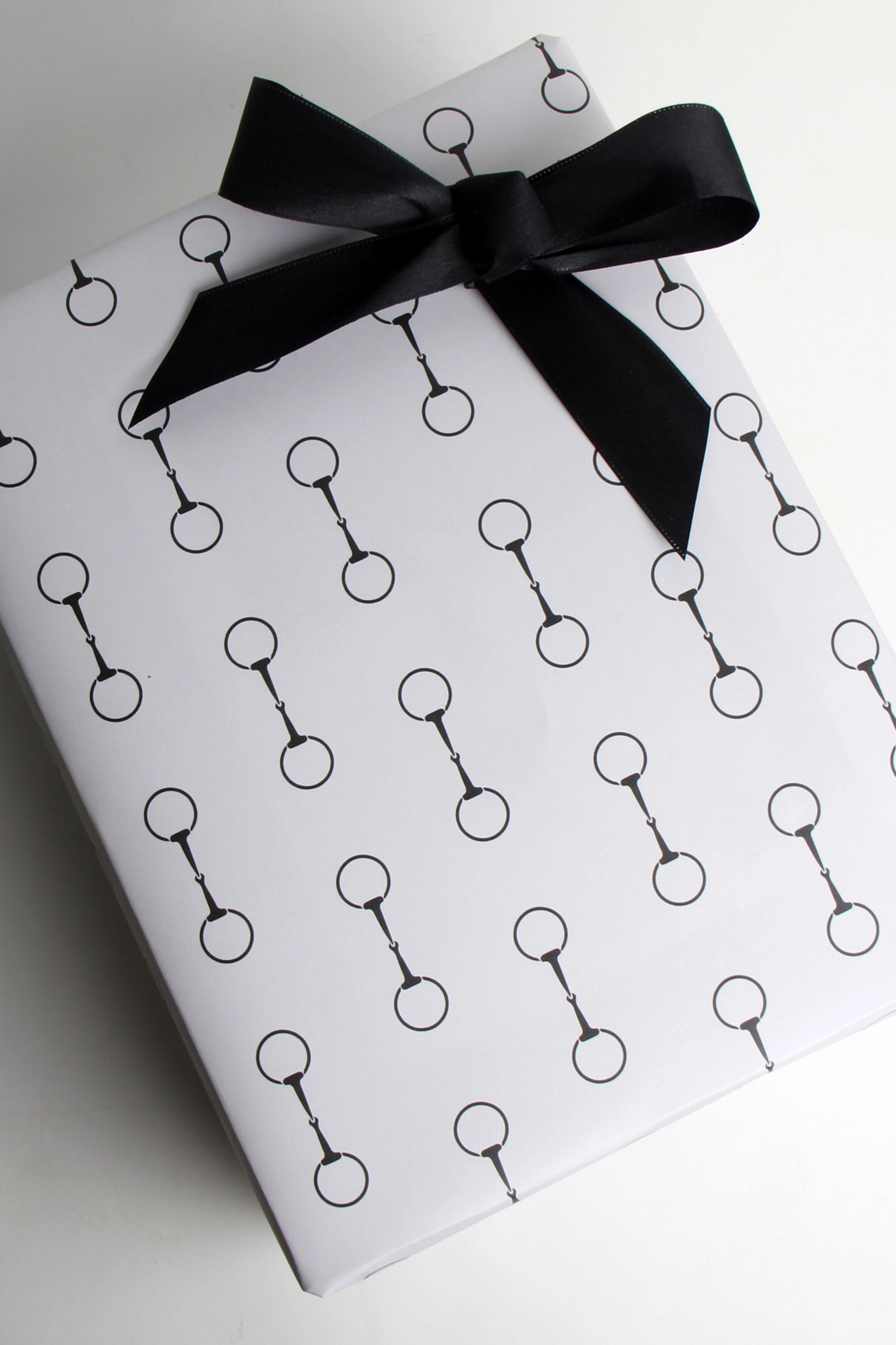 Elegant equestrian gift wrapping paper set featuring a repeating black horse bit pattern on premium textured white paper. Luxury horse-themed gift wrap sheets made in the USA—perfect for horse lovers, equestrian gifts, and stylish holiday packaging.