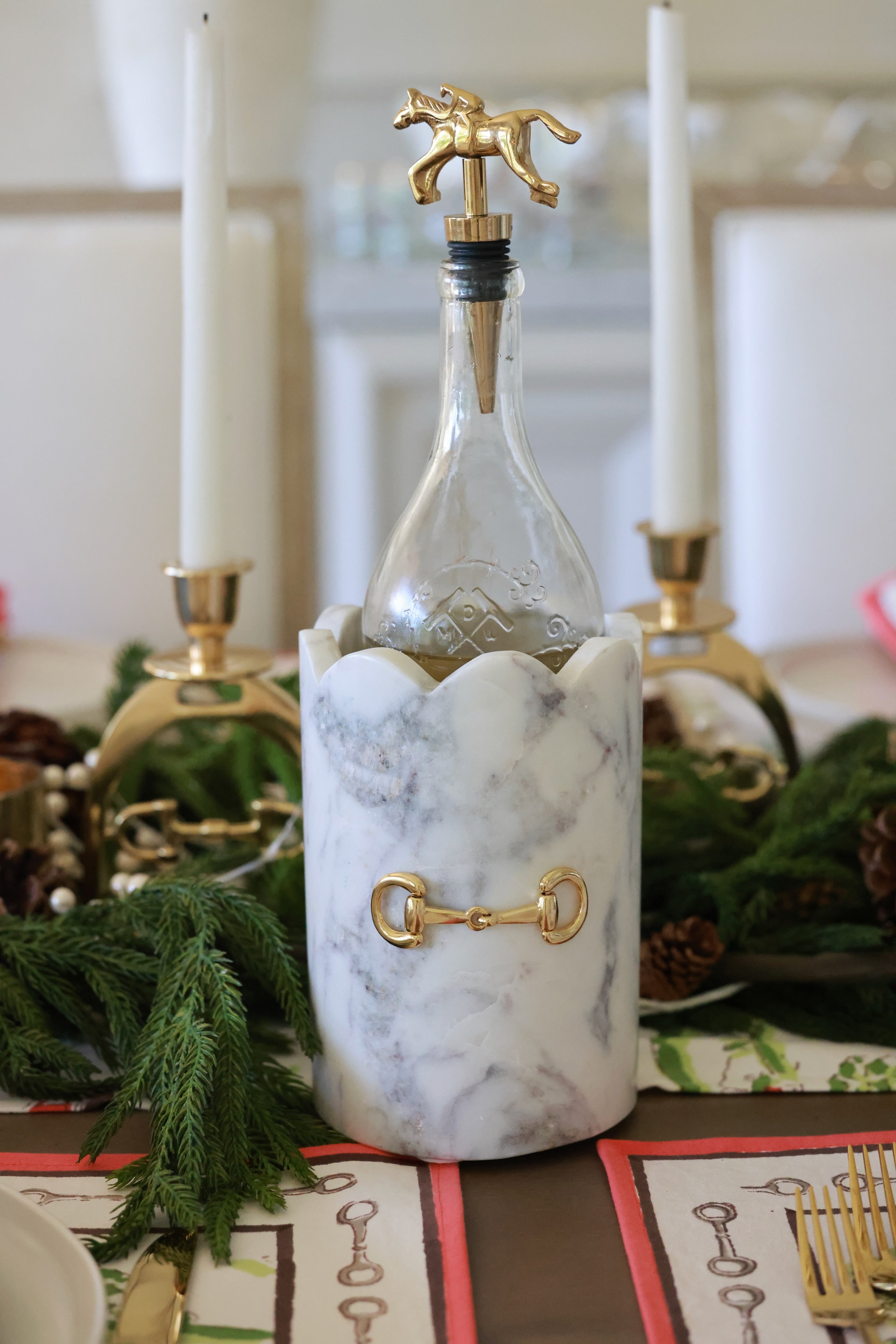 Luxurious white marble D-ring scalloped wine chiller with polished gold horse bit hardware, handcrafted for an elegant equestrian-inspired home. The cylindrical marble design features subtle natural veining, perfect for chilling wine or champagne, or as a stylish horse-themed vase or utensil holder.