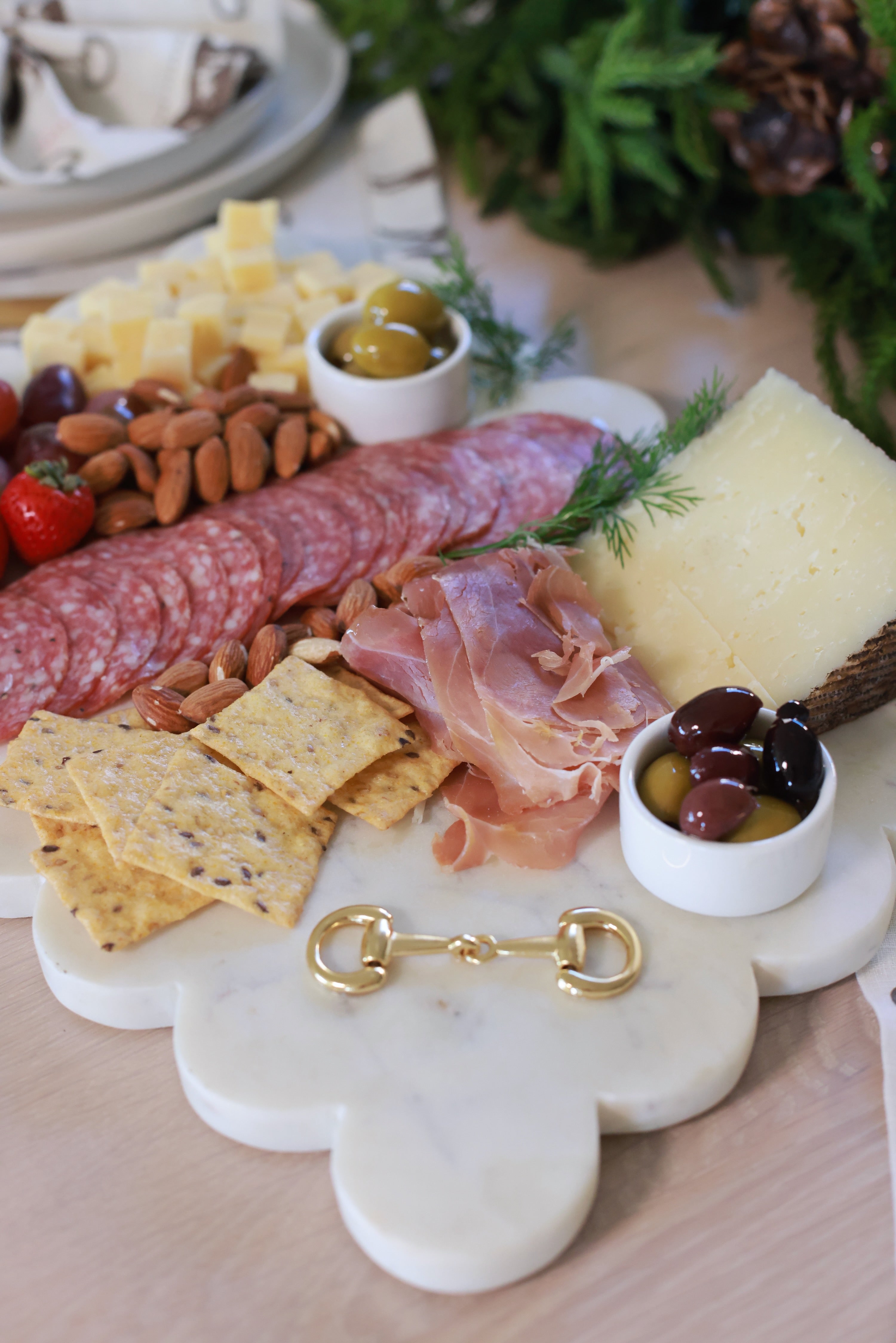 Elegant white marble scalloped serving board with gold D-ring bit, styled in an equestrian-themed kitchen. The handcrafted marble board features subtle natural veining and polished gold hardware, displayed with cheese, fruits, and wine accents. Perfect as a horse-inspired charcuterie tray or decorative equestrian home accent.