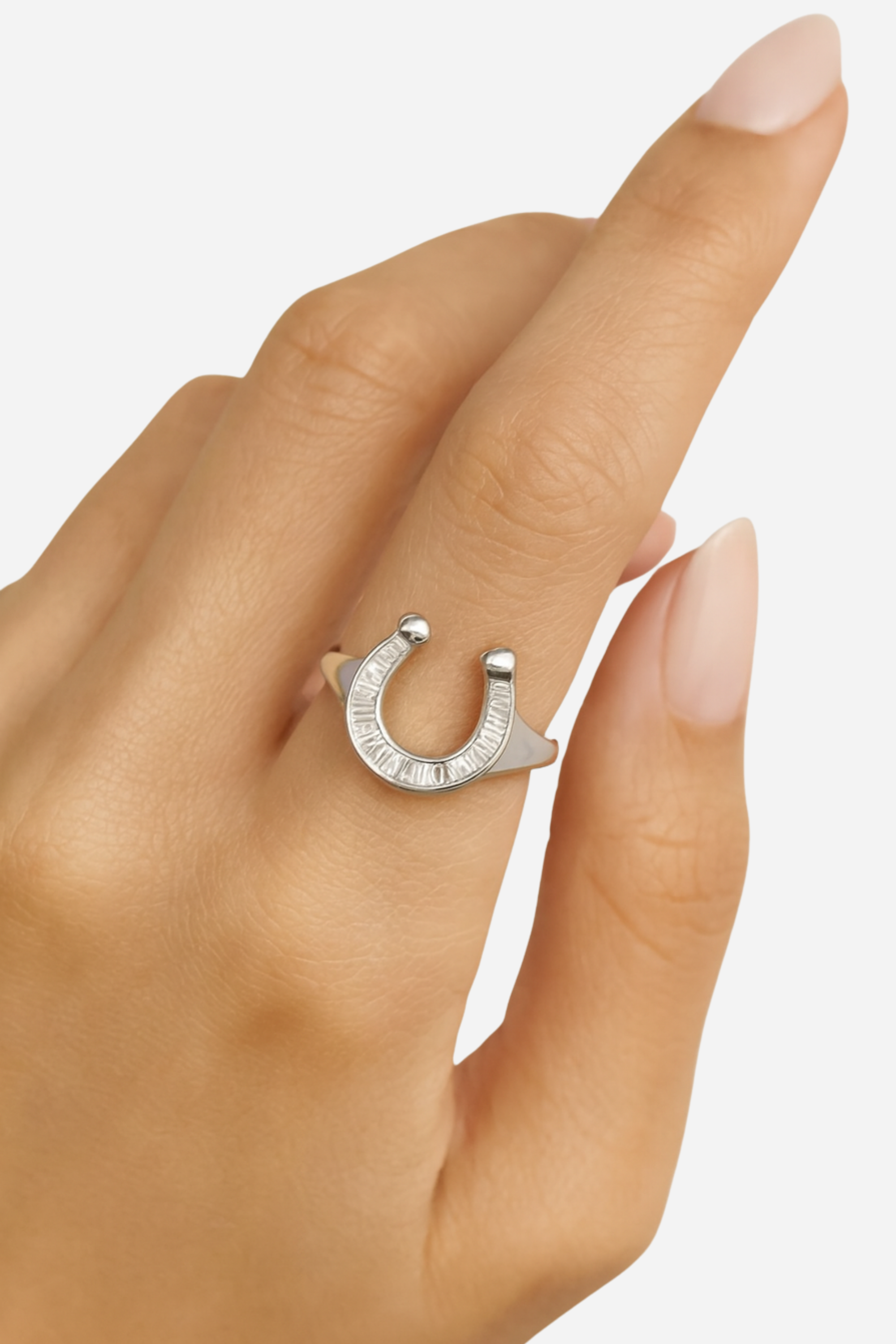Silver horseshoe ring on a person's finger with a blurred background