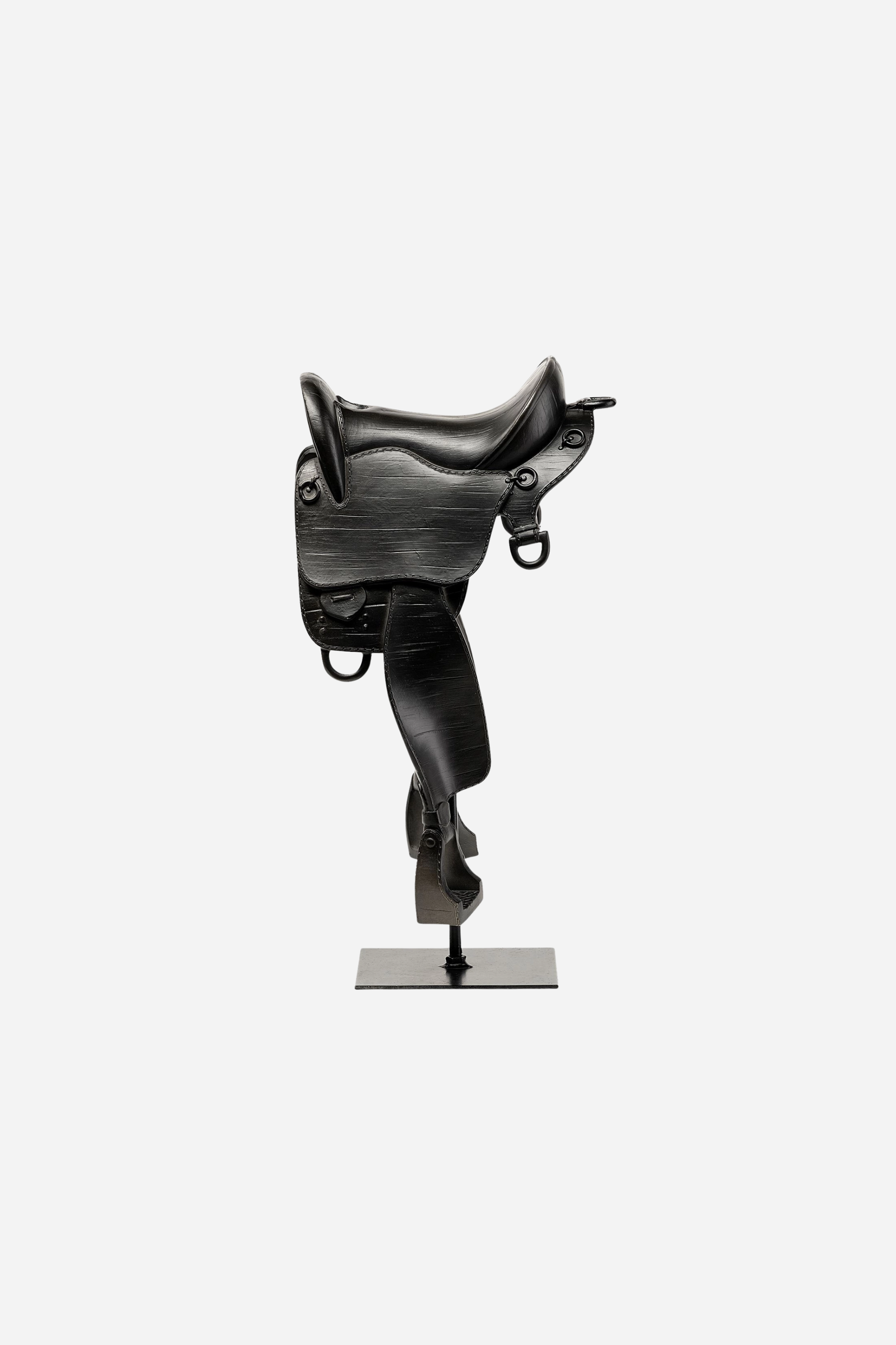 A matte black English-style equestrian saddle decor piece crafted from resin and metal, featuring fine detailing that mimics real saddle stitching and hardware. The saddle sits atop a sleek black metal rod and square base, standing 17 inches tall. Its minimalist, modern design evokes traditional riding gear while serving as a bold centerpiece for equestrian-themed home decor.