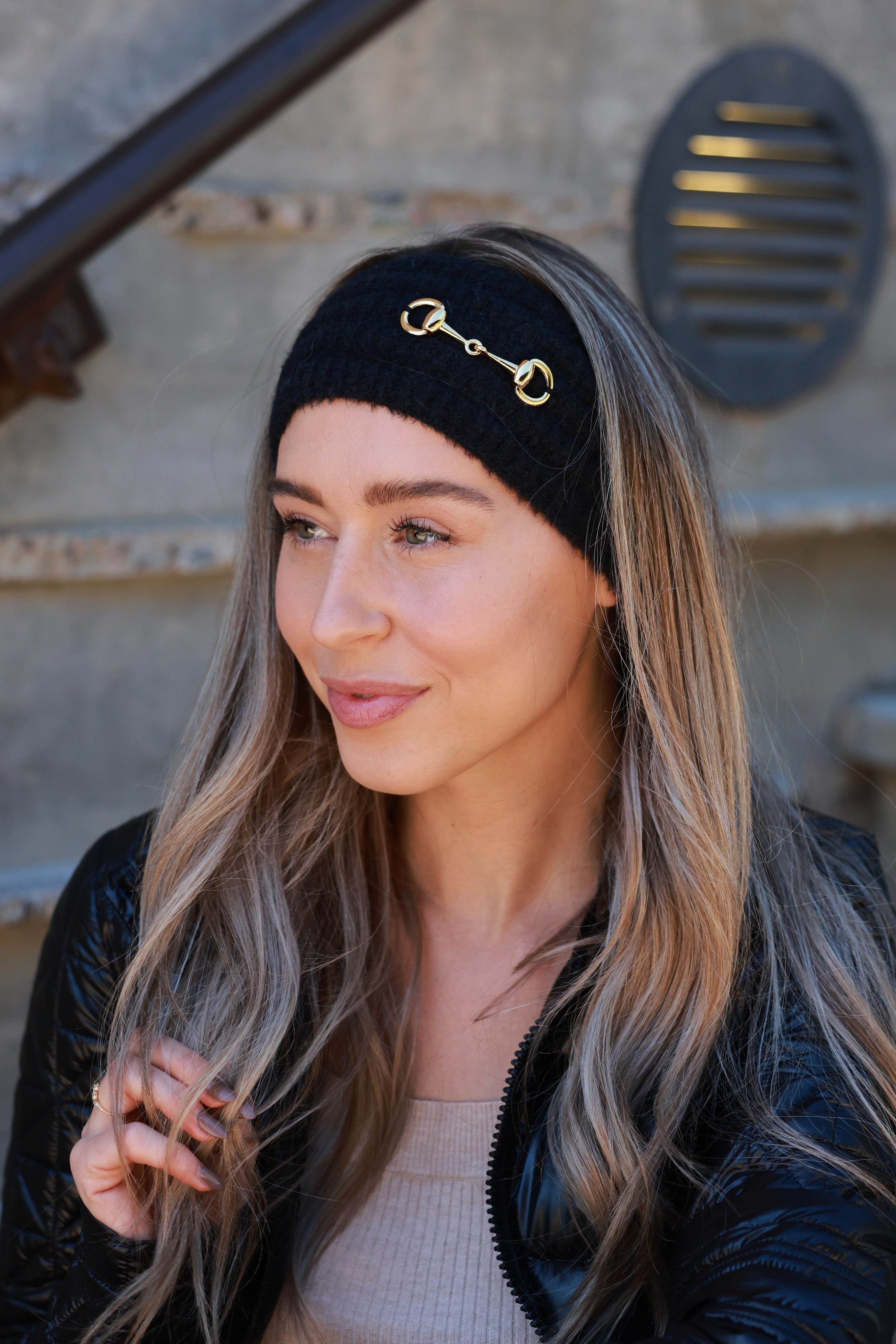 Black Elsie Knit Headband featuring soft, stretchy knit fabric and a gold bit accent. Comfortable, secure fit adds a touch of equestrian elegance to any cold-weather look.