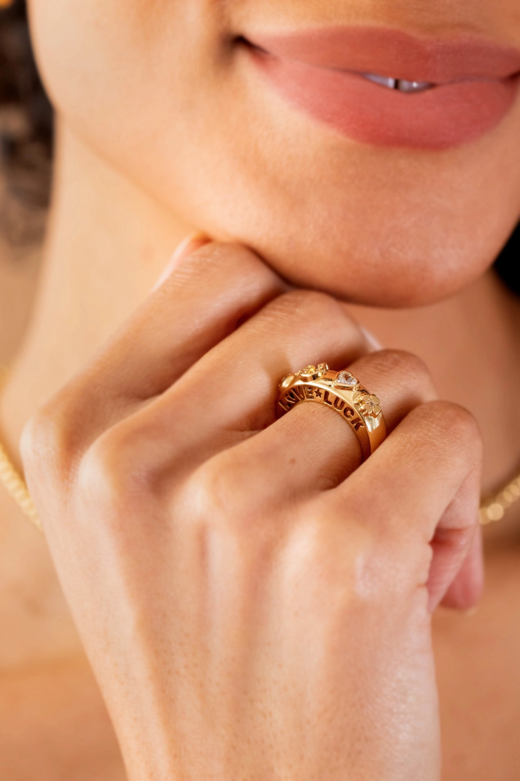 Gold-plated domed ring engraved with “Love” and “Luck,” featuring crystal-accented lucky symbols including a horseshoe and four-leaf clover.