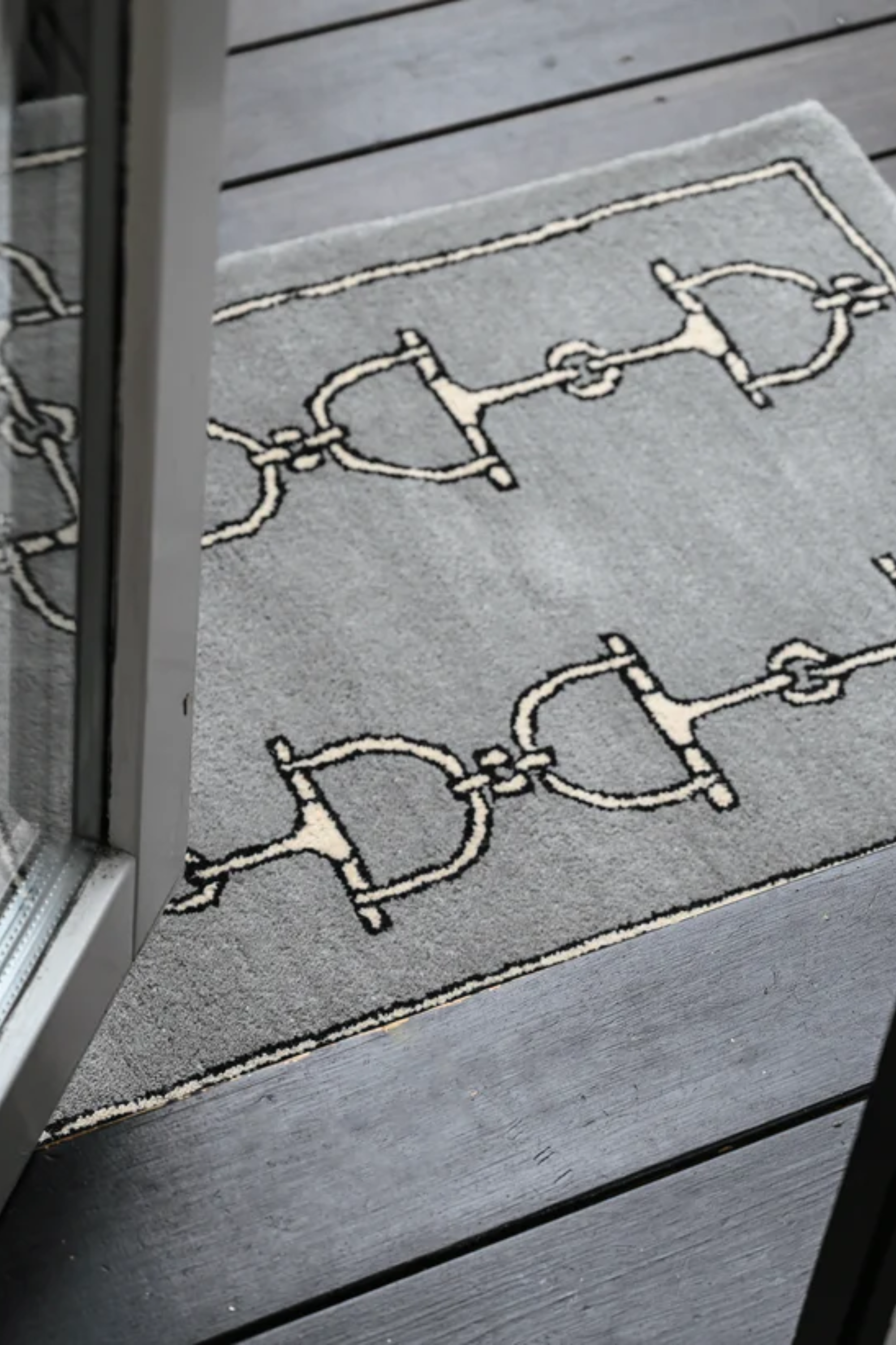 Gray rug with a pattern of bridles and bits in two vertical rows. Framed by a simple border, the design adds a touch of elegance and classic style. equestrian home décor, horse themed rug, luxury equestrian barn accessories, tufted wool rug, saddle room décor, barn entryway mat, horse bit design rug, equestrian gift ideas, stylish horse barn décor
