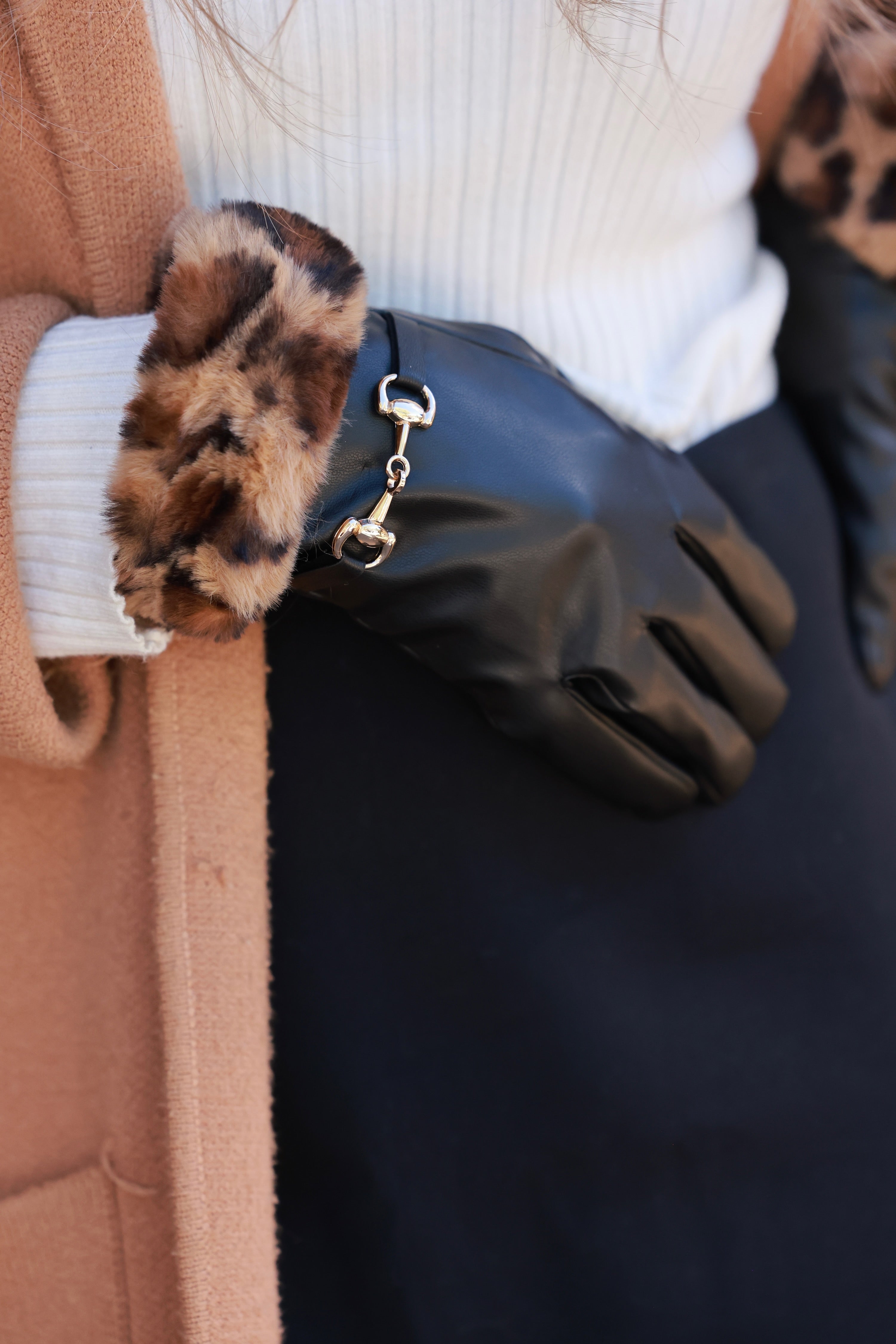 Meredith Horse Bit Gloves crafted from supple polyurethane leather with soft faux-fur lining, chic leopard print cuffs, and polished gold horse bit detail. Elegant equestrian cold-weather accessory combining warmth, style, and sophistication.