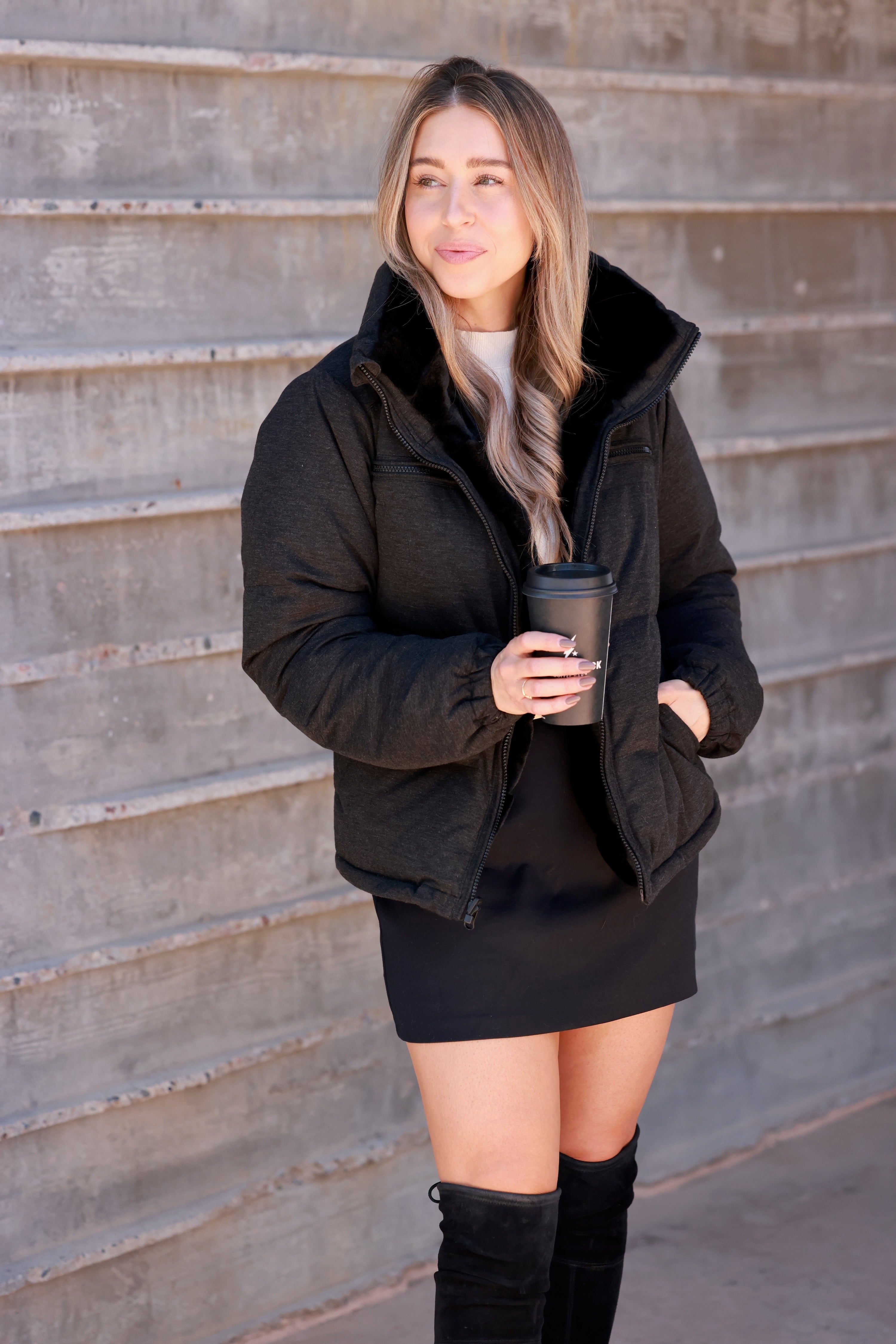 Black Reversible Puffer Jacket featuring a sleek exterior and ultra-soft faux fur interior for versatile styling. Down-filled for warmth with adjustable drawstring waist, hidden hood, and thumbholes for comfort. A stylish, adventure-ready equestrian-inspired winter coat perfect from trails to town.