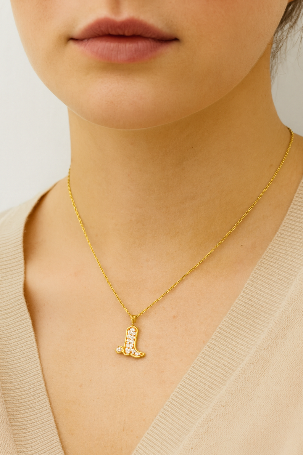Gold necklace with a pendant worn by a person against a neutral background