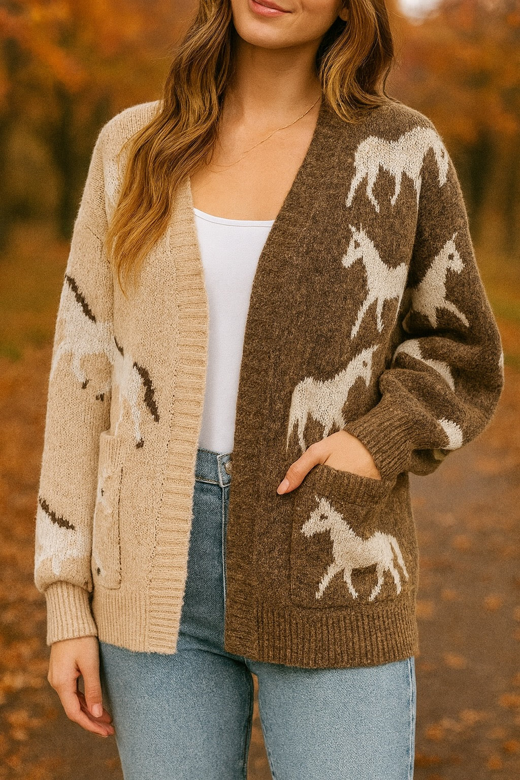 Woman wearing an asymmetric open-front cardigan in brown and beige with white horse patterns. This cozy equestrian cardigan blends rustic western style with casual horse girl apparel, soft, stretchy knit perfect for everyday wear.