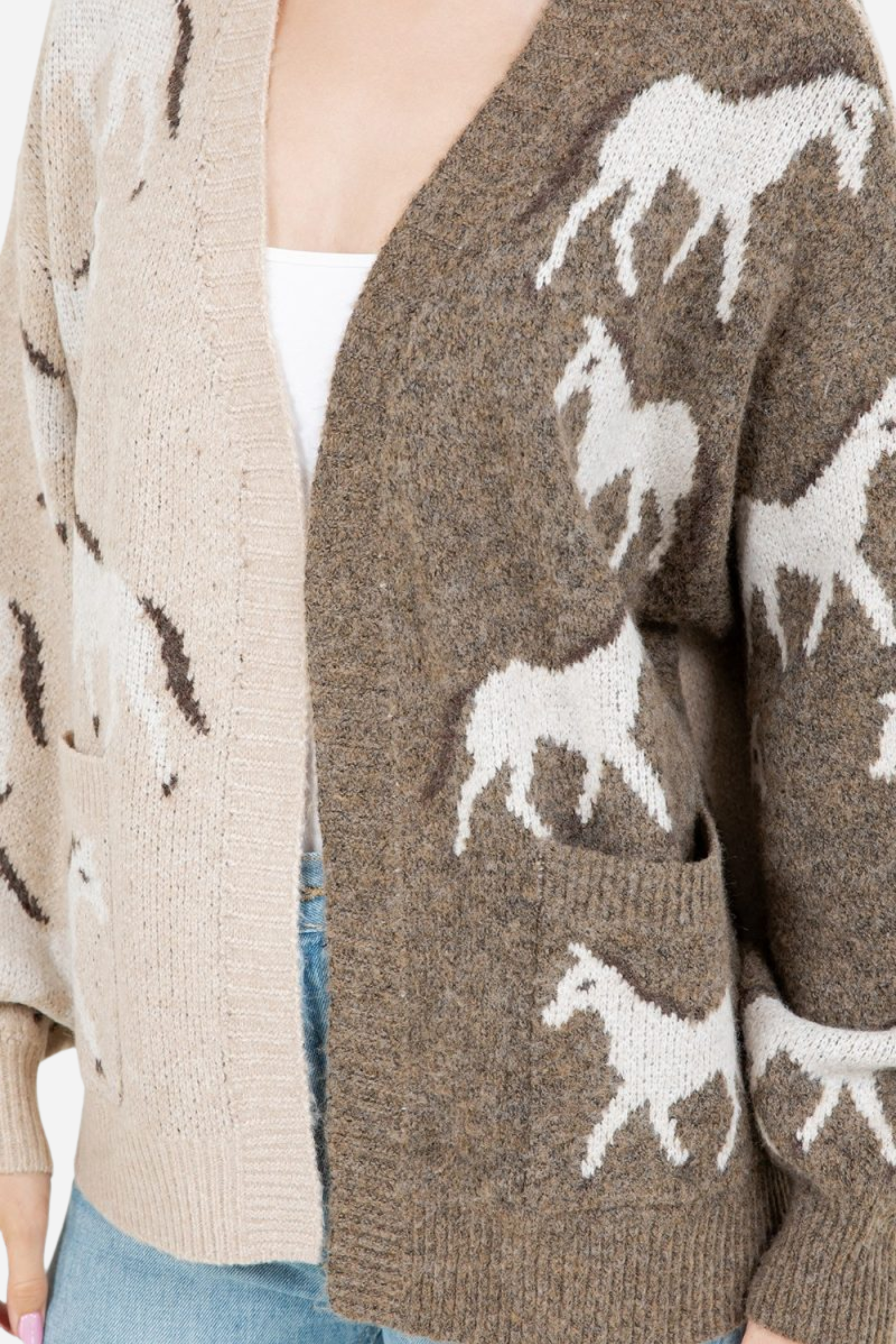 Woman wearing an asymmetric open-front cardigan in brown and beige with white horse patterns. This cozy equestrian cardigan blends rustic western style with casual horse girl apparel, soft, stretchy knit perfect for everyday wear.
