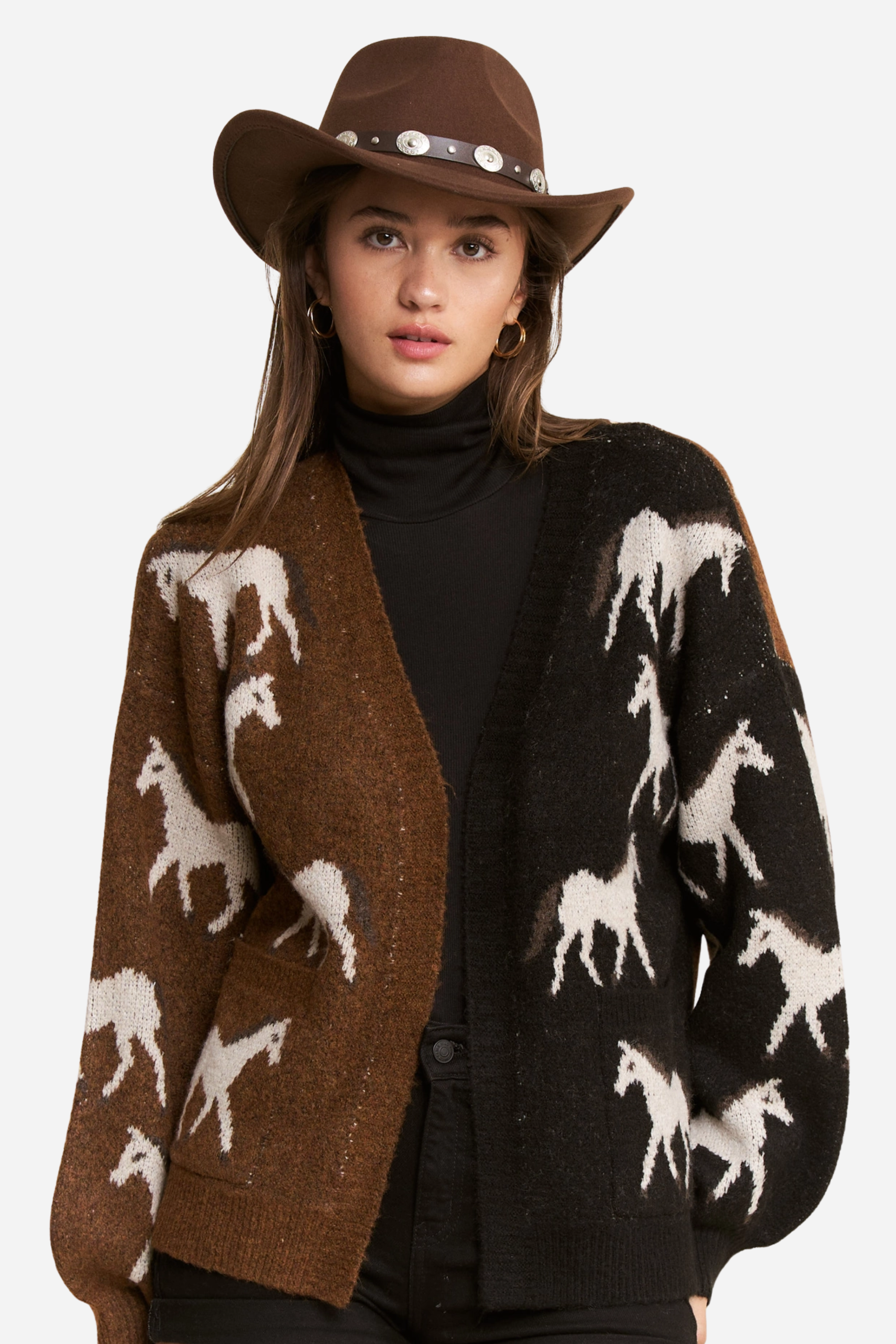 Person wearing a two-tone knit horse cardigan in brown and black, featuring white prancing horse patterns on the front and back. This soft, stretchy equestrian sweater includes long sleeves, cuffed trim, and pockets, perfect for horse girl apparel and western-inspired outfits.