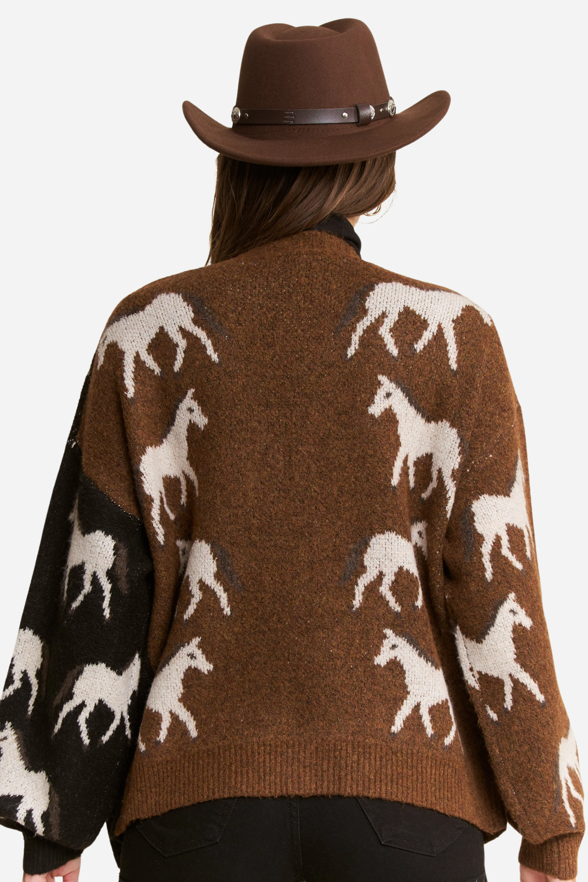 Person wearing a two-tone knit horse cardigan in brown and black, featuring white prancing horse patterns on the front and back. This soft, stretchy equestrian sweater includes long sleeves, cuffed trim, and pockets, perfect for horse girl apparel and western-inspired outfits.