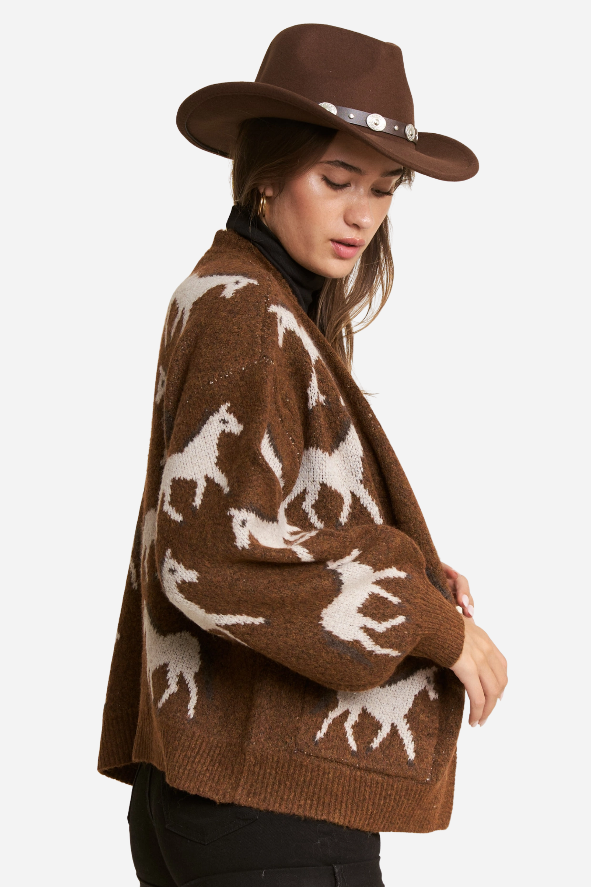 Person wearing a two-tone knit horse cardigan in brown and black, featuring white prancing horse patterns on the front and back. This soft, stretchy equestrian sweater includes long sleeves, cuffed trim, and pockets, perfect for horse girl apparel and western-inspired outfits.