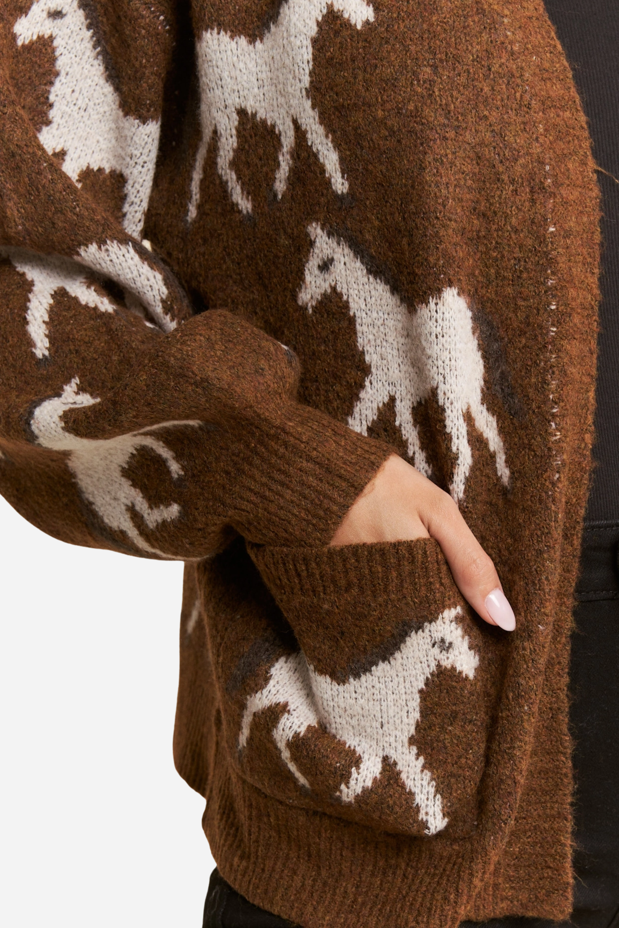 Person wearing a two-tone knit horse cardigan in brown and black, featuring white prancing horse patterns on the front and back. This soft, stretchy equestrian sweater includes long sleeves, cuffed trim, and pockets, perfect for horse girl apparel and western-inspired outfits.