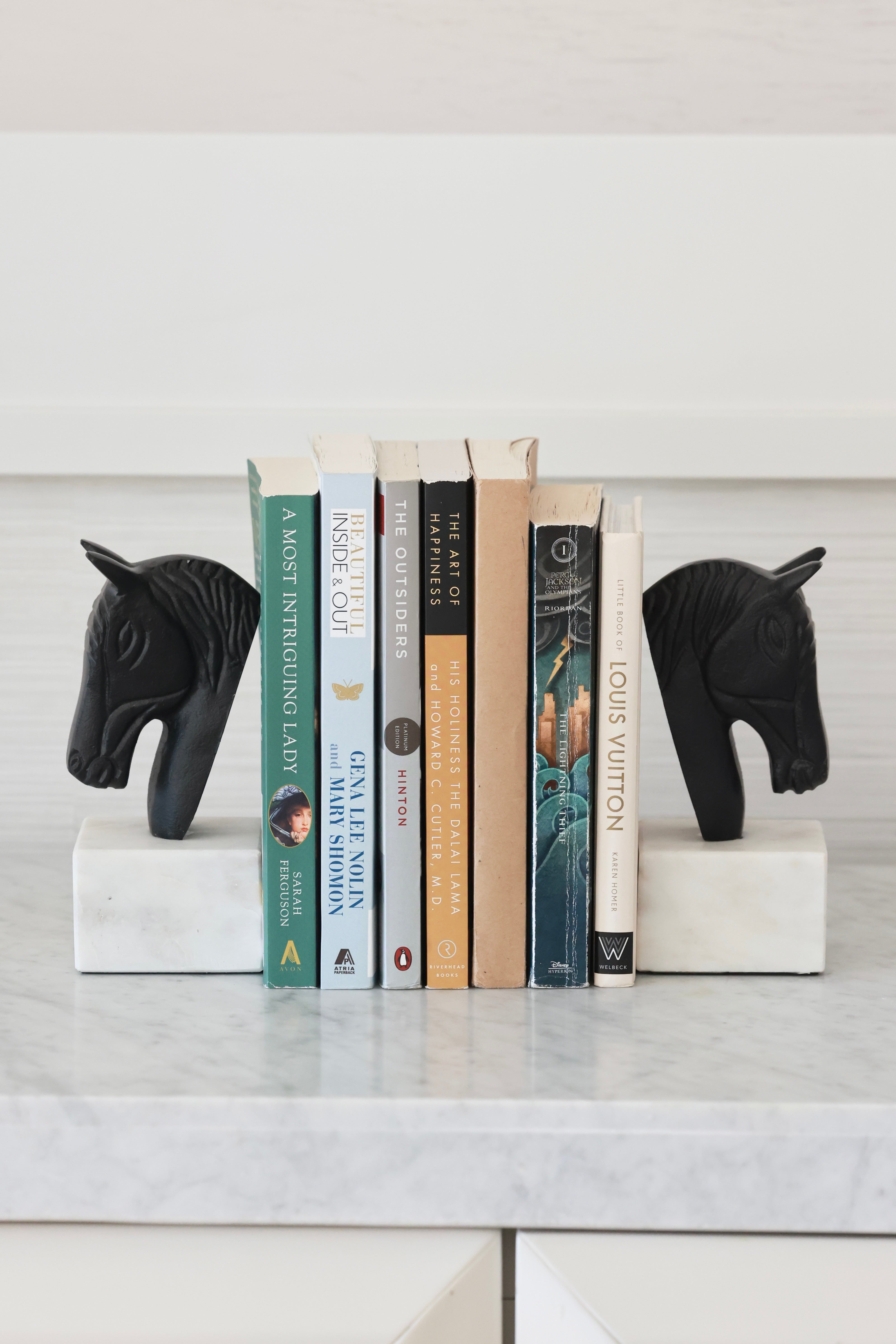 Set of two metal horse head bookends with sleek black and white aluminum design and solid marble bases. Elegant equestrian-inspired home décor perfect for elevating a bookshelf, office, or home library while securely holding books with timeless style.