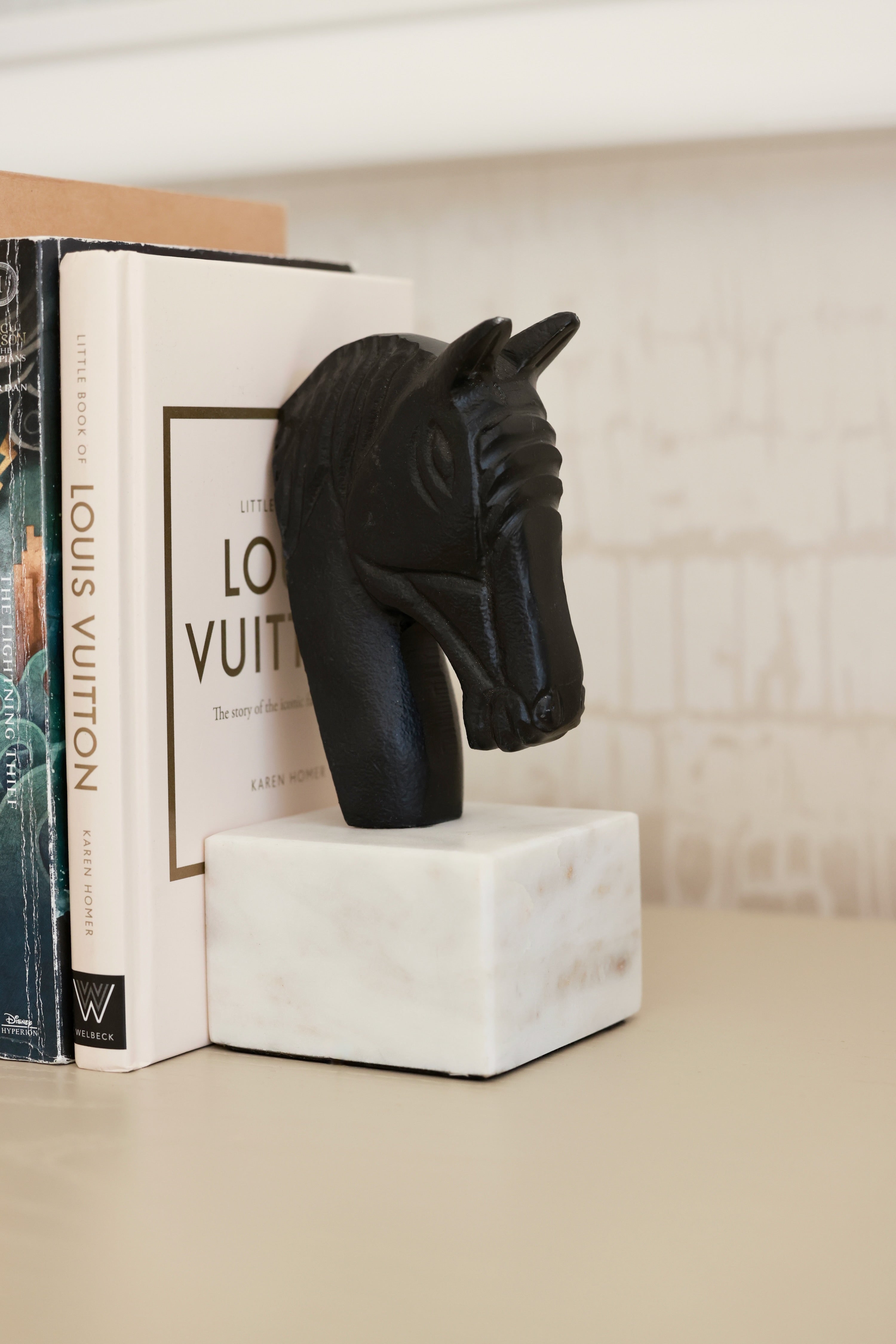 Set of two metal horse head bookends with sleek black and white aluminum design and solid marble bases. Elegant equestrian-inspired home décor perfect for elevating a bookshelf, office, or home library while securely holding books with timeless style.