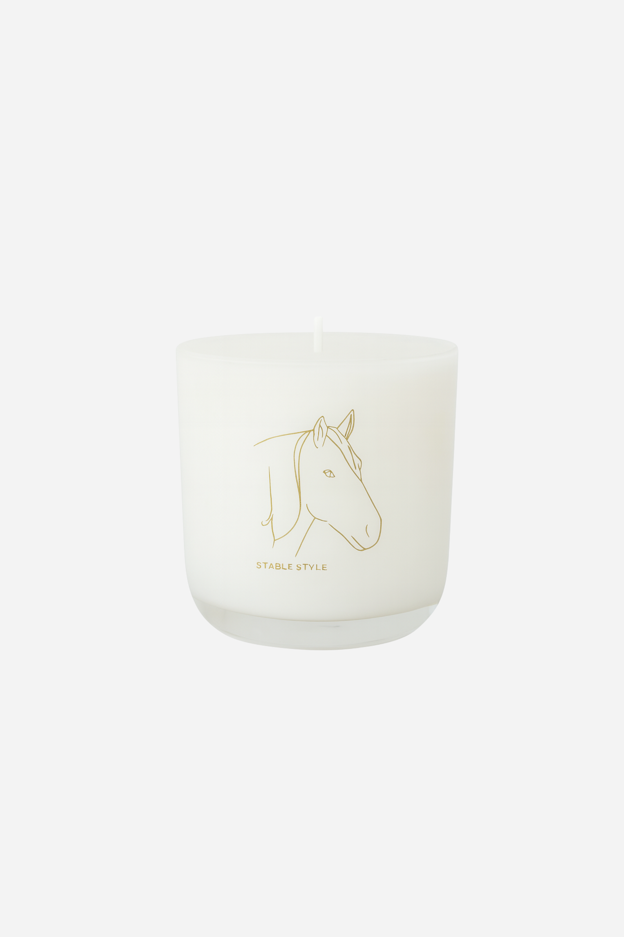 White soy wax candle labeled 'Spirit,' featuring elegant horse illustrations, set on marble with matchsticks nearby. Fragrance opens with bright lemon and lime, transitions into tropical fruit and Tahitian gardenia, and finishes with sweet jam and warm musk. Hand-poured in a 10-ounce clear glass vessel with gold accents, offering 60+ hours of burn time.