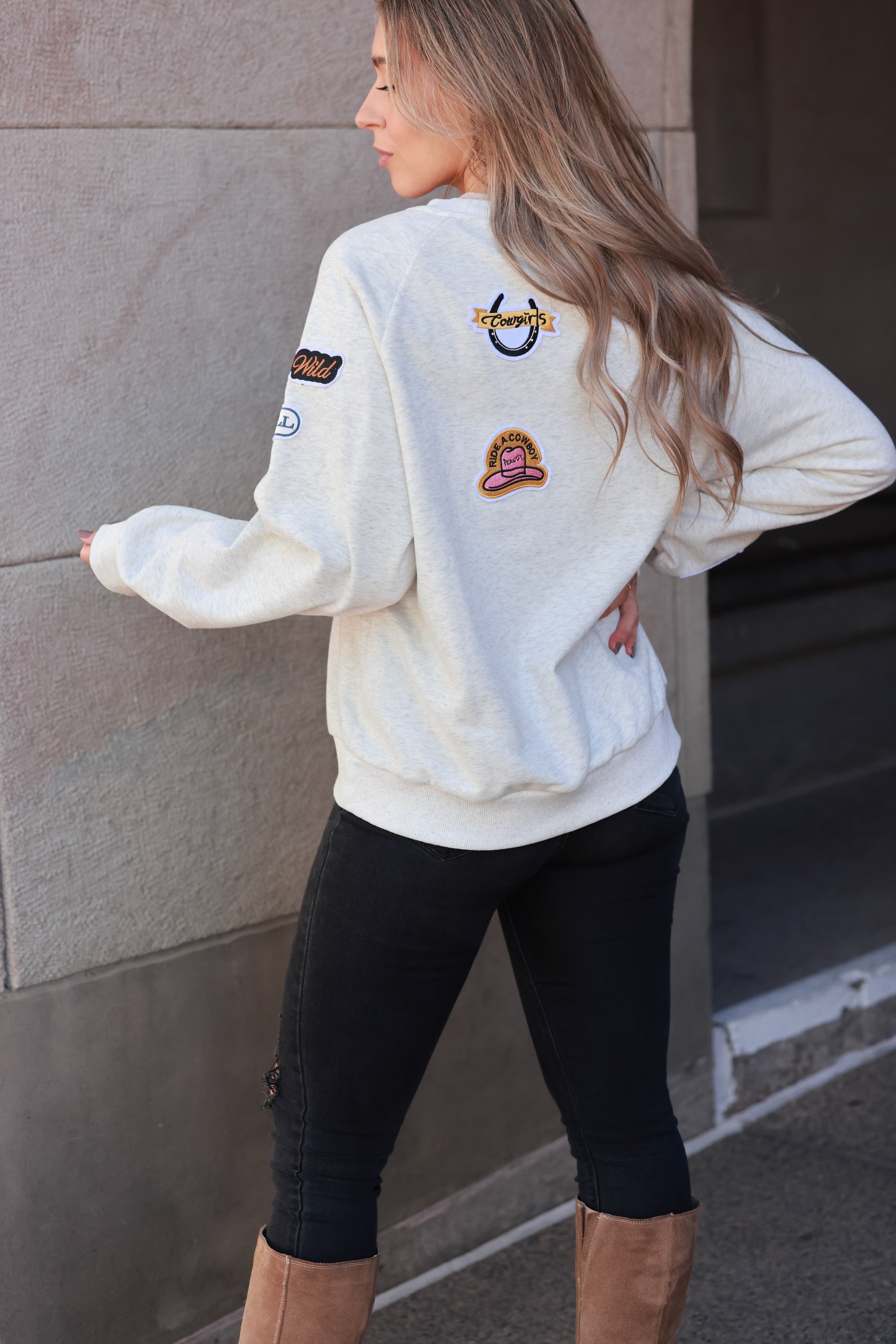Stay Wild Patch Sweatshirt crafted from soft cotton with raglan sleeves and ribbed cuffs, neck, and hemline. Features a curated mix of western-inspired patches for a bold, adventurous equestrian look. True to size with an optional oversized fit for casual horse-girl style.