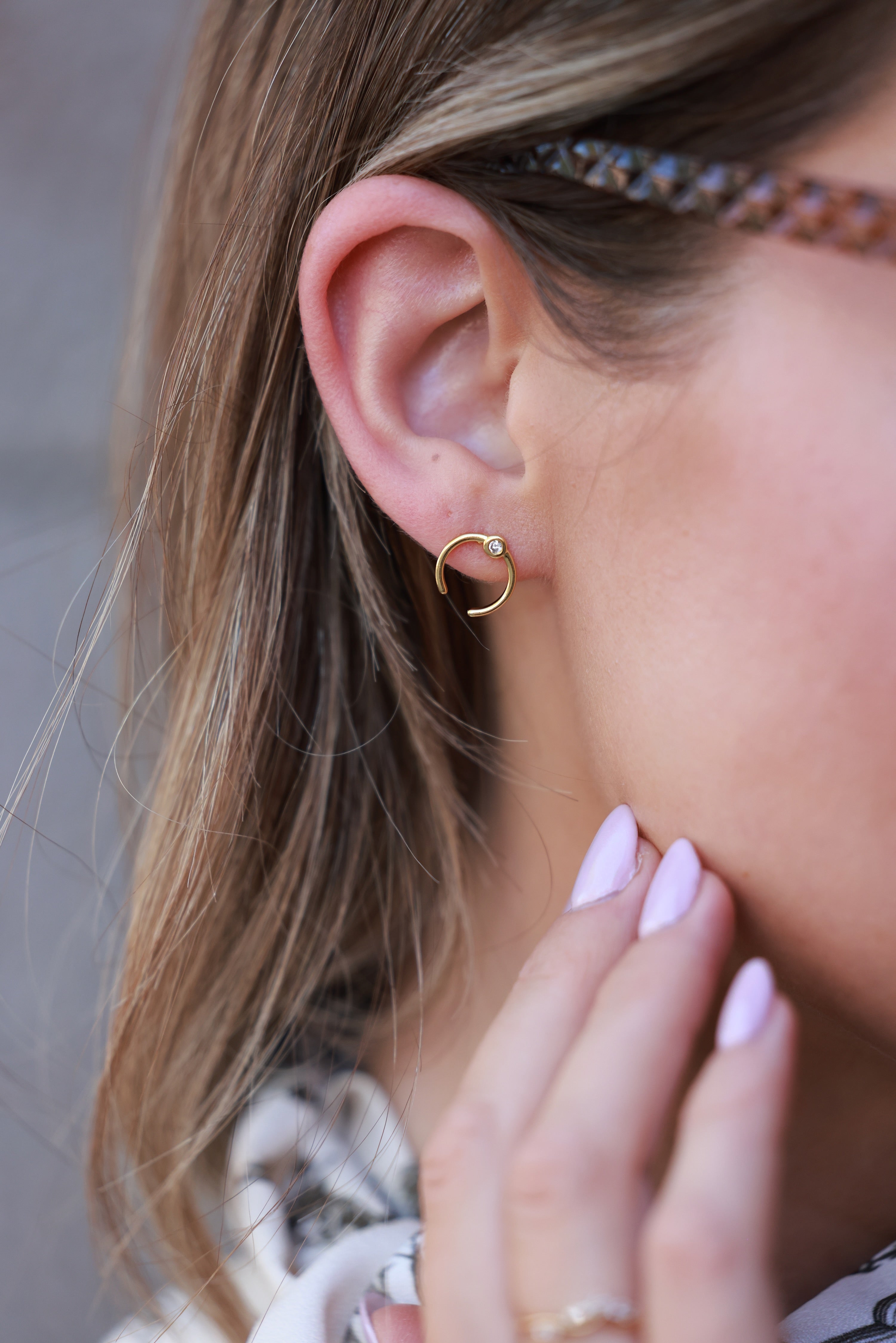 Close-up of a person wearing a gold hoop earring with a neutral background - equestrian inspired jewelry, horse girl accessories, dainty equestrian jewelry, horseshoe inspired design, small gifts for horse girls