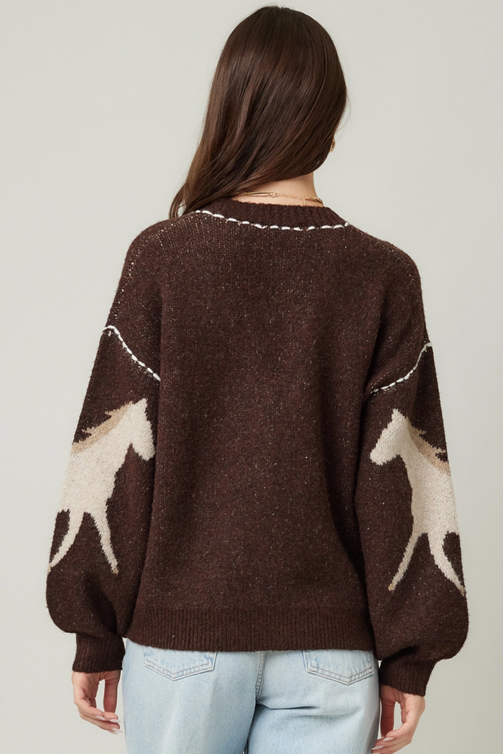 Woman wearing a brown cardigan with deer pattern and light blue jeans on a plain background - Horse knit cardigan, Brown western cardigan, Cowgirl graphic sweater, Oversized horse print cardigan, Equestrian boutique knitwear