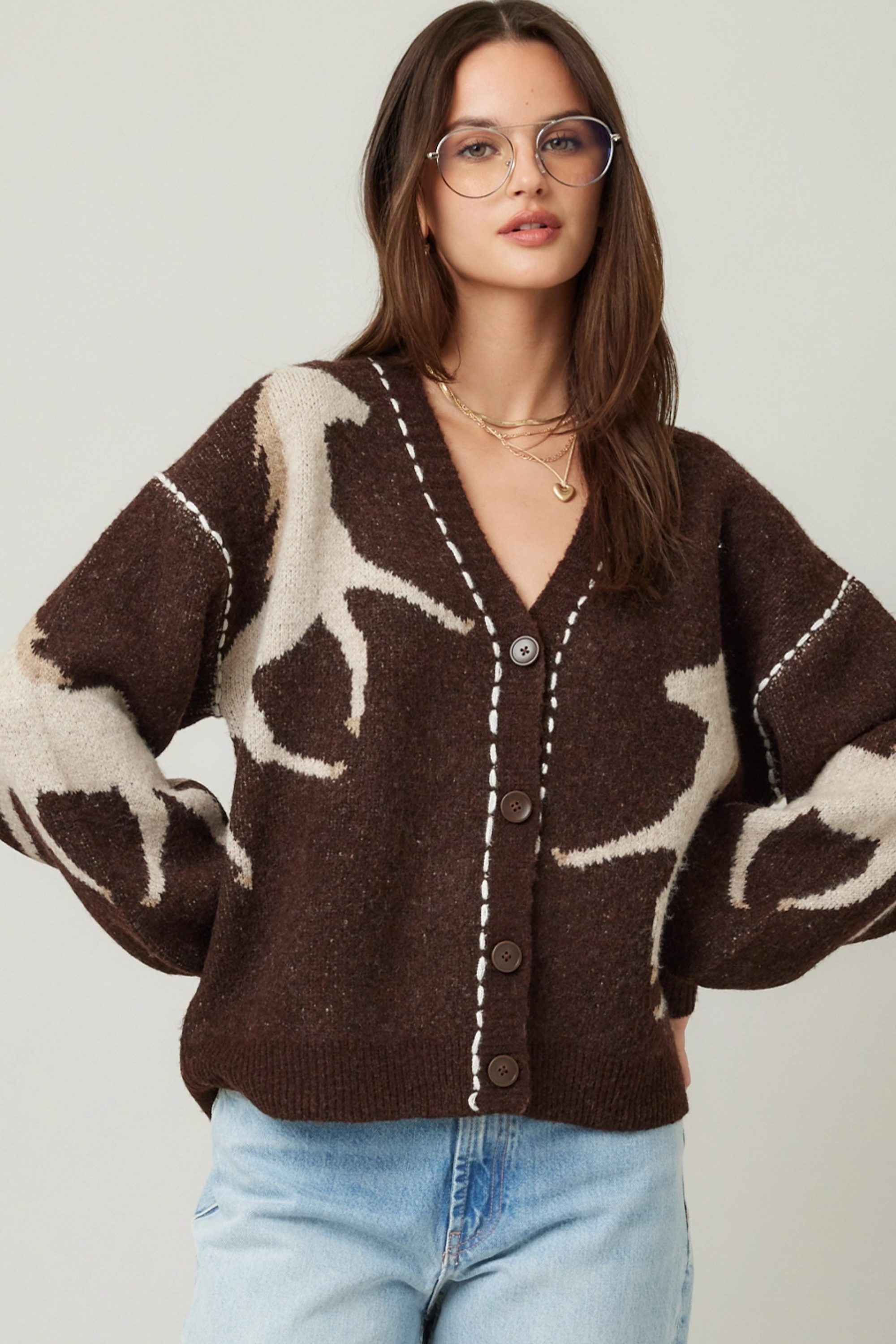 Woman wearing a brown cardigan with deer pattern and light blue jeans on a plain background - Horse knit cardigan, Brown western cardigan, Cowgirl graphic sweater, Oversized horse print cardigan, Equestrian boutique knitwear