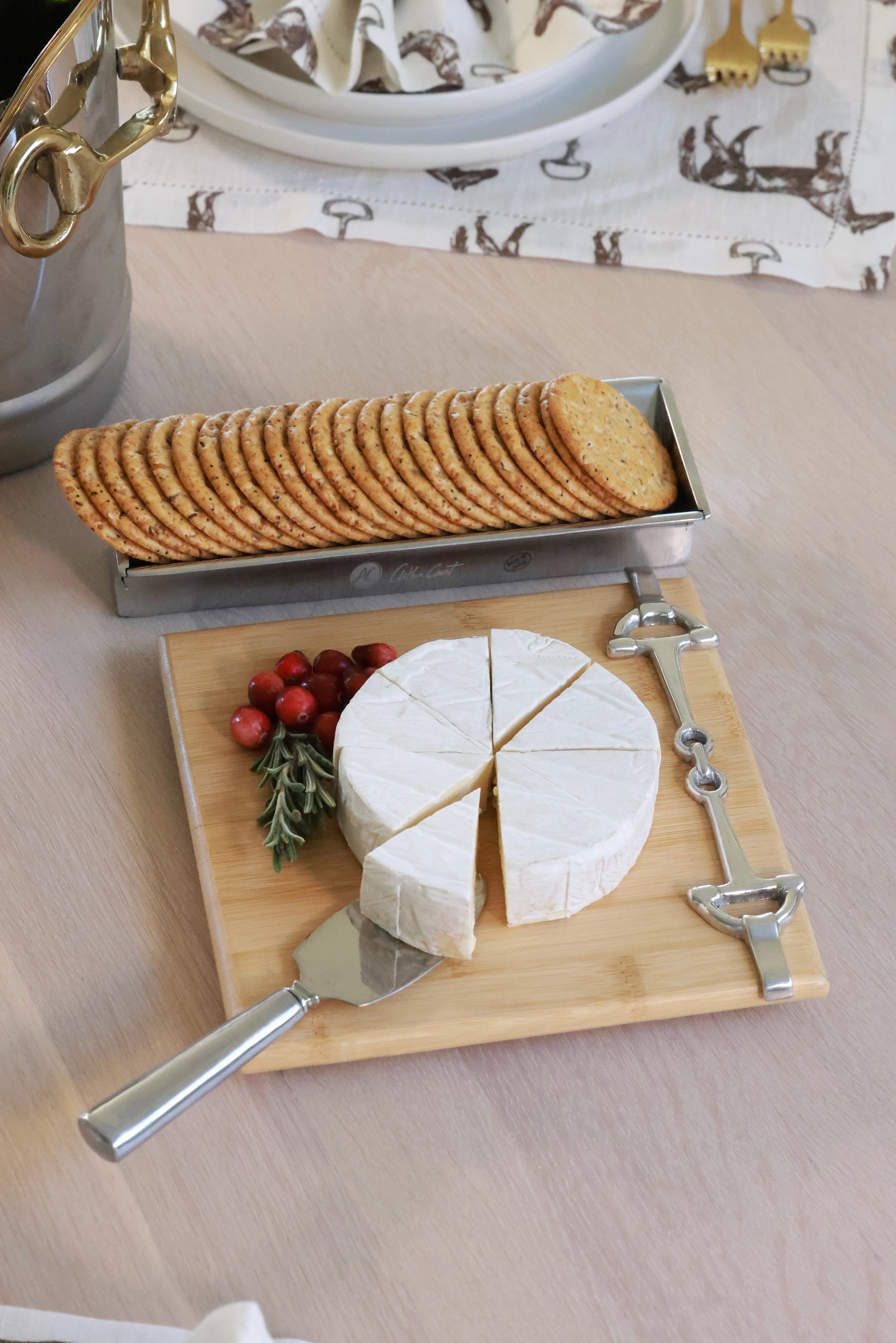 Well Served Set by Arthur Court featuring a bamboo serving board with a silver alloy horse bit accent, paired with a matching aluminum cheese knife and cracker tray. Elegant equestrian-themed serveware perfect for entertaining or gifting.