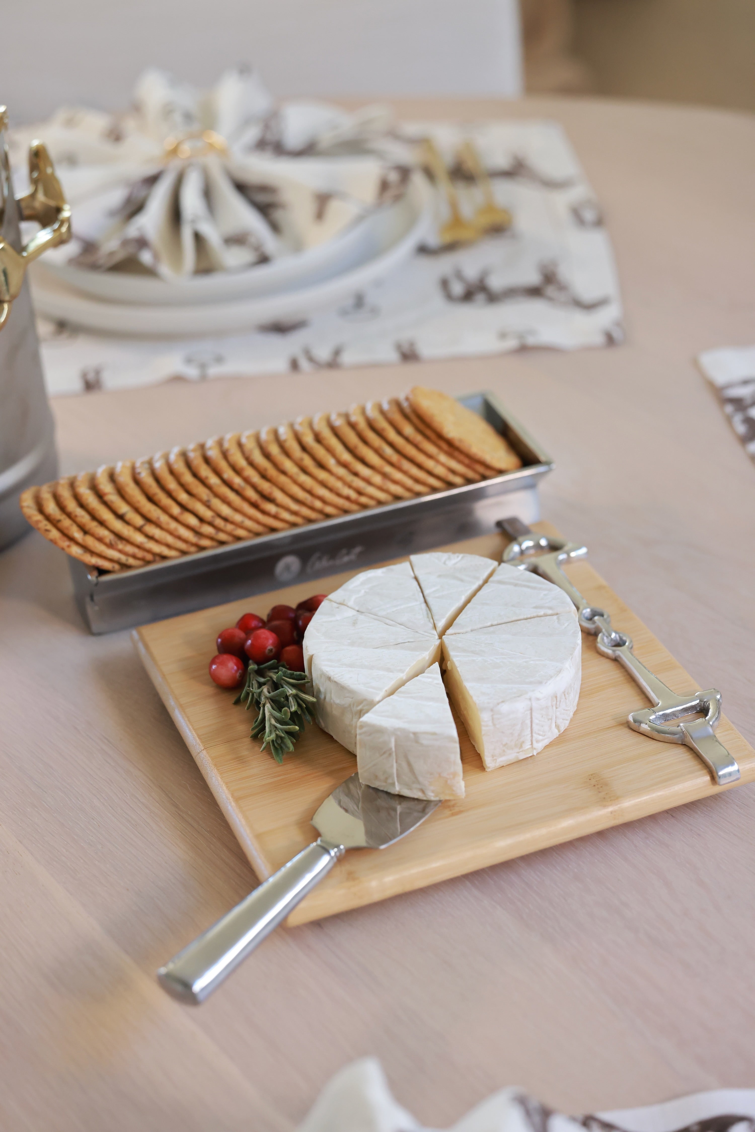 Well Served Set by Arthur Court featuring a bamboo serving board with a silver alloy horse bit accent, paired with a matching aluminum cheese knife and cracker tray. Elegant equestrian-themed serveware perfect for entertaining or gifting.
