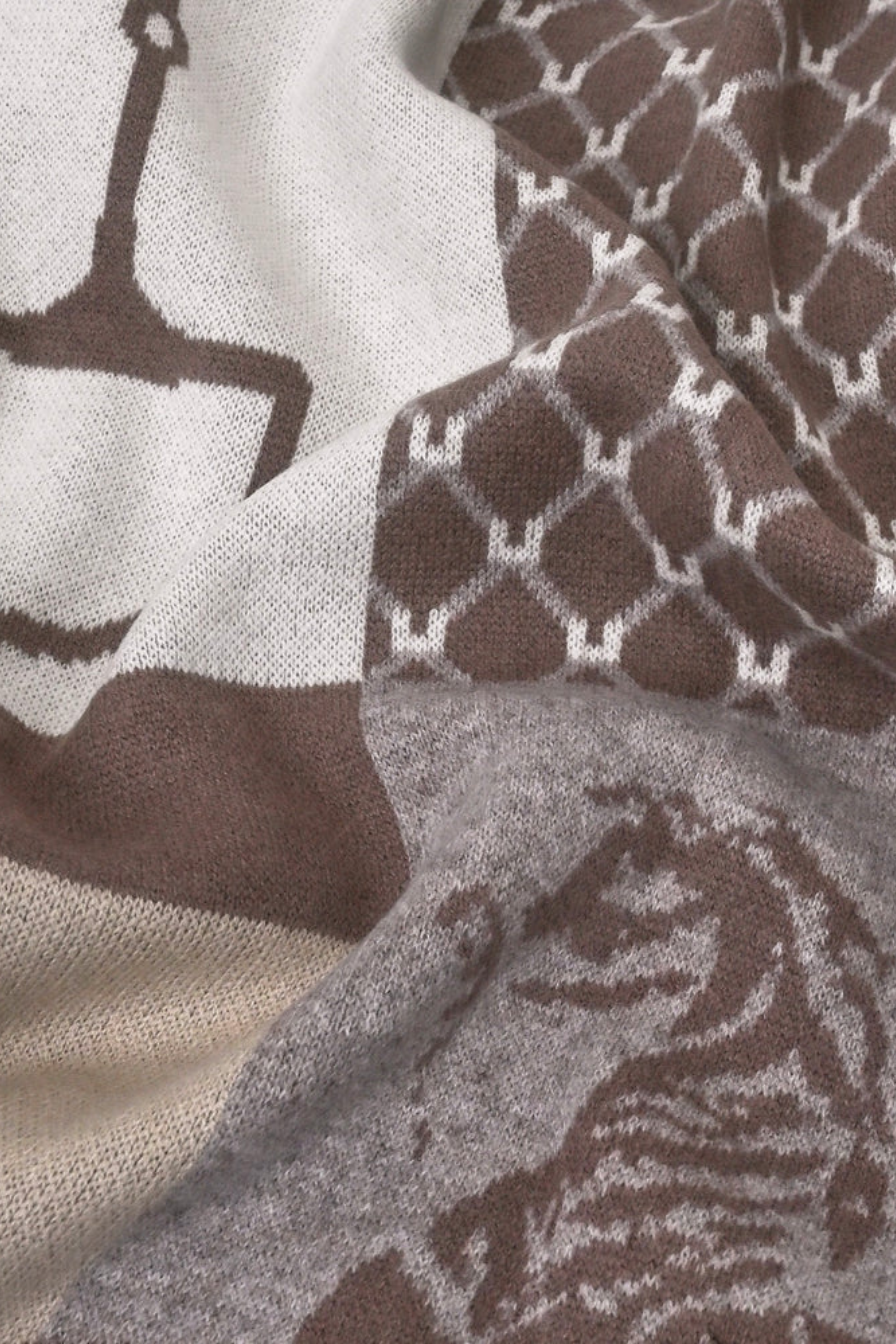Stylish jacquard-knit cashmere poncho with an equestrian-inspired design featuring a horse, riding gear, and geometric patterns in warm off-white, beige, and taupe tones. The piece evokes a rustic yet refined aesthetic, perfect for elevating everyday or evening looks.
