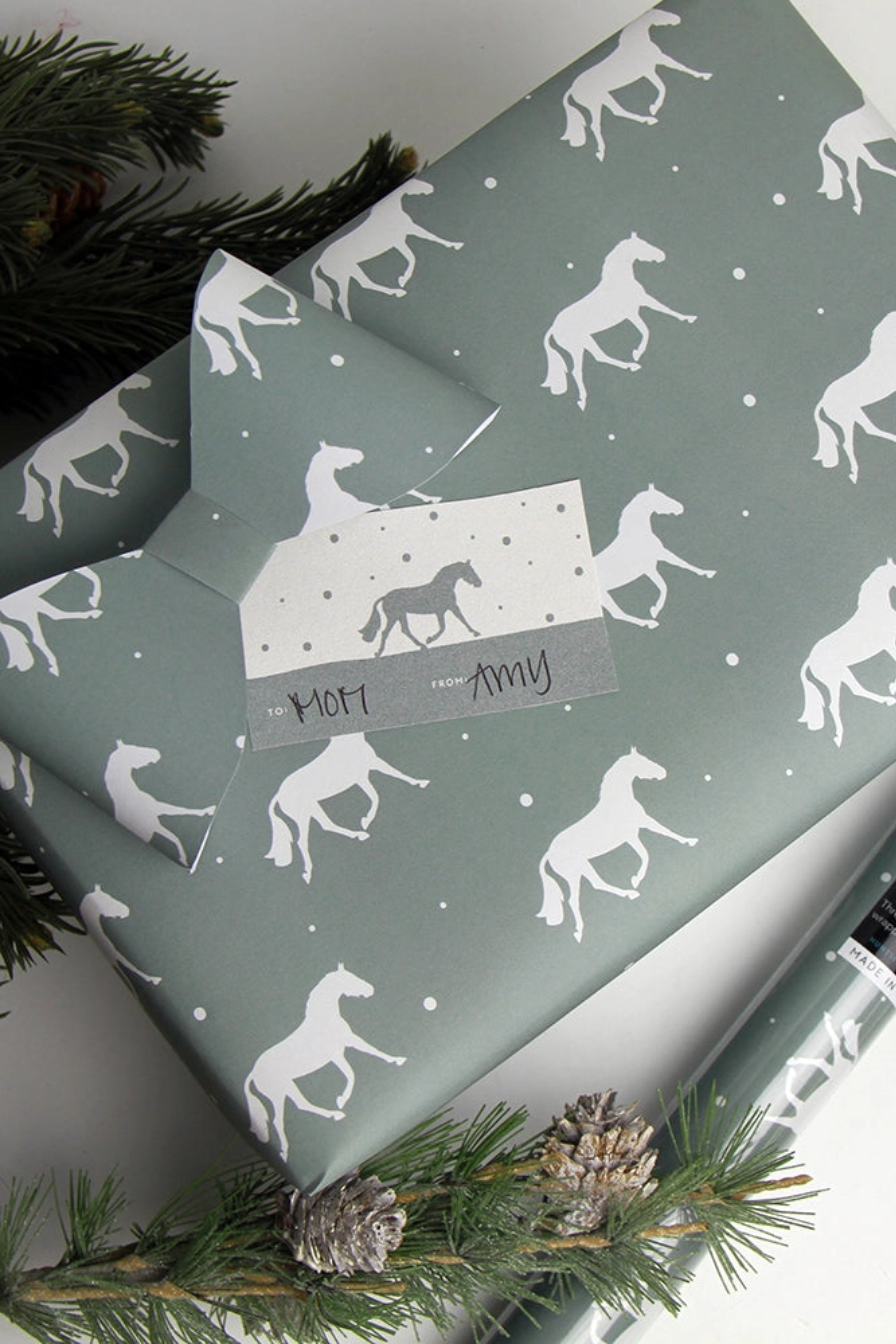 Set of three luxury equestrian gift wrap sheets featuring a repeating pattern of elegant trotting horses on a soft sage green background, printed on high-quality textured paper. Perfect horse themed wrapping paper for winter gifts, horse lovers, and equestrian events. Made in the USA. equestrian gift wrapping paper, horse wrapping paper, winter horse gift wrap sheets, sage green horse gift wrap, luxury horse themed wrapping paper, equestrian stationery, horse lover gift wrap, elegant equestrian