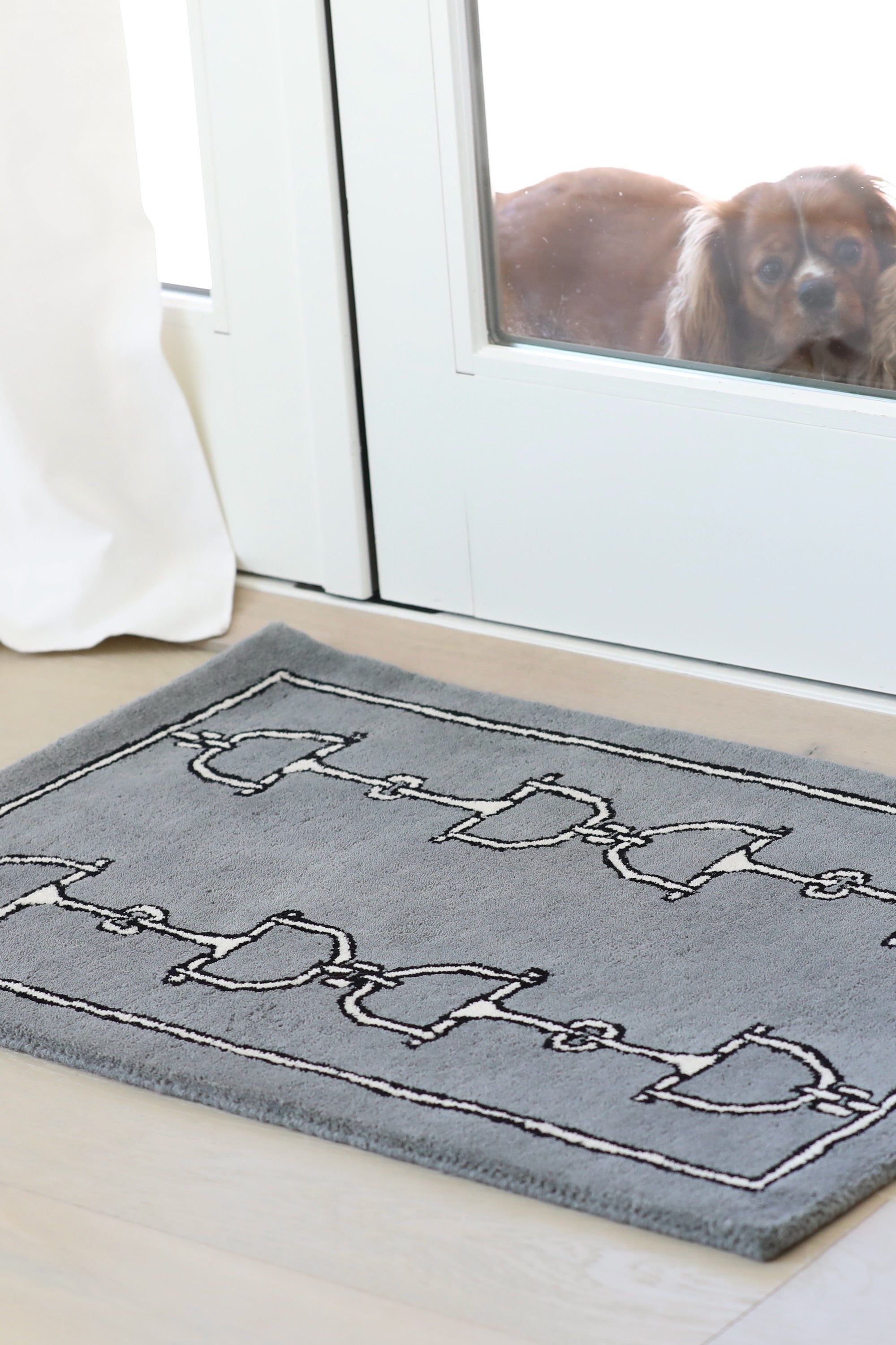 Gray rug with a pattern of bridles and bits in two vertical rows. Framed by a simple border, the design adds a touch of elegance and classic style. equestrian home décor, horse themed rug, luxury equestrian barn accessories, tufted wool rug, saddle room décor, barn entryway mat, horse bit design rug, equestrian gift ideas, stylish horse barn décor