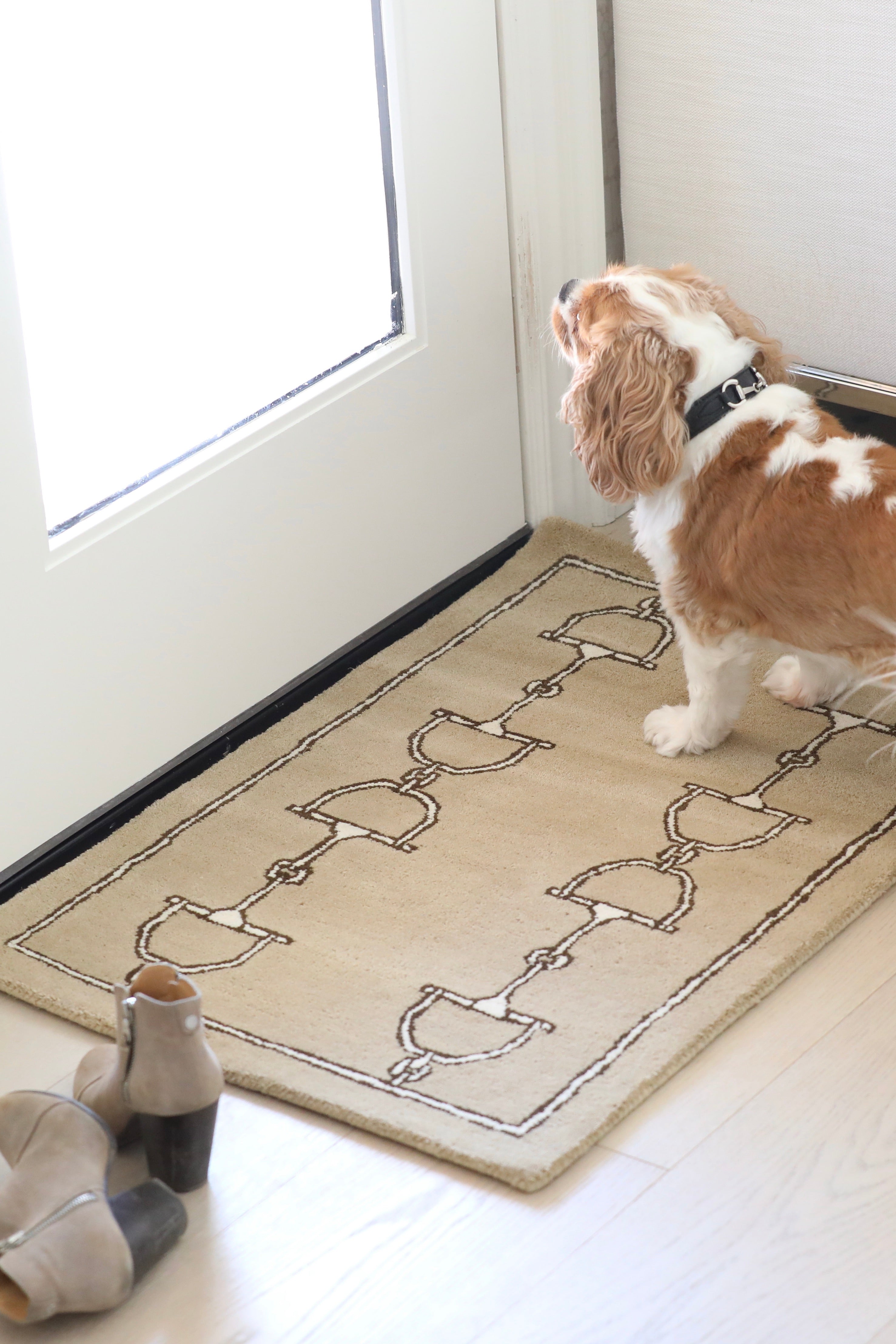 Tan rug featuring a pattern of dark brown horse bits aligned vertically in two columns with a matching dark brown border. Simple and elegant design. equestrian inspired snaffle bit print rug horse themed home decor